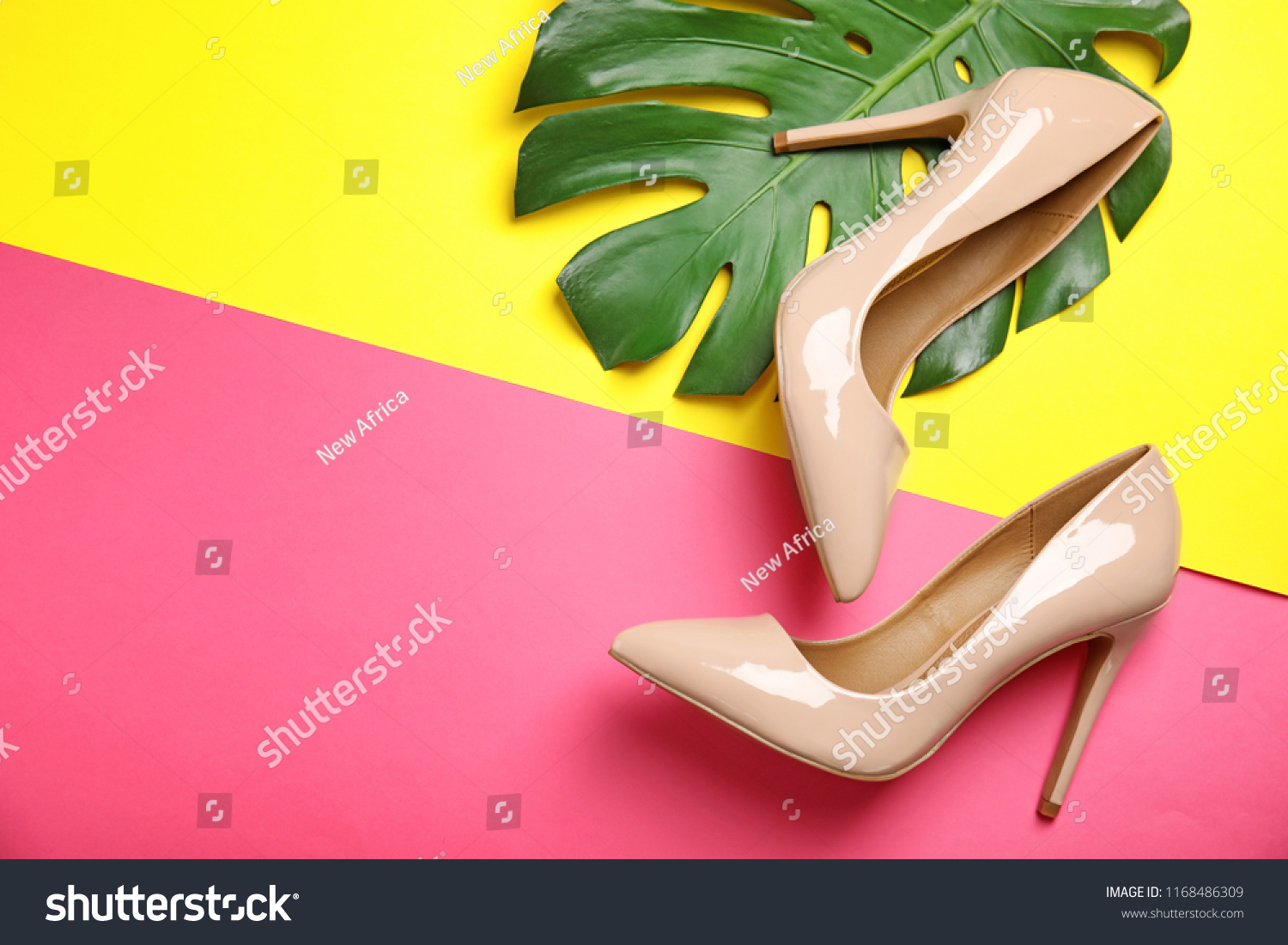 Pair of beautiful shoes with monstera leaf and space for text on color background, top view #1168486309