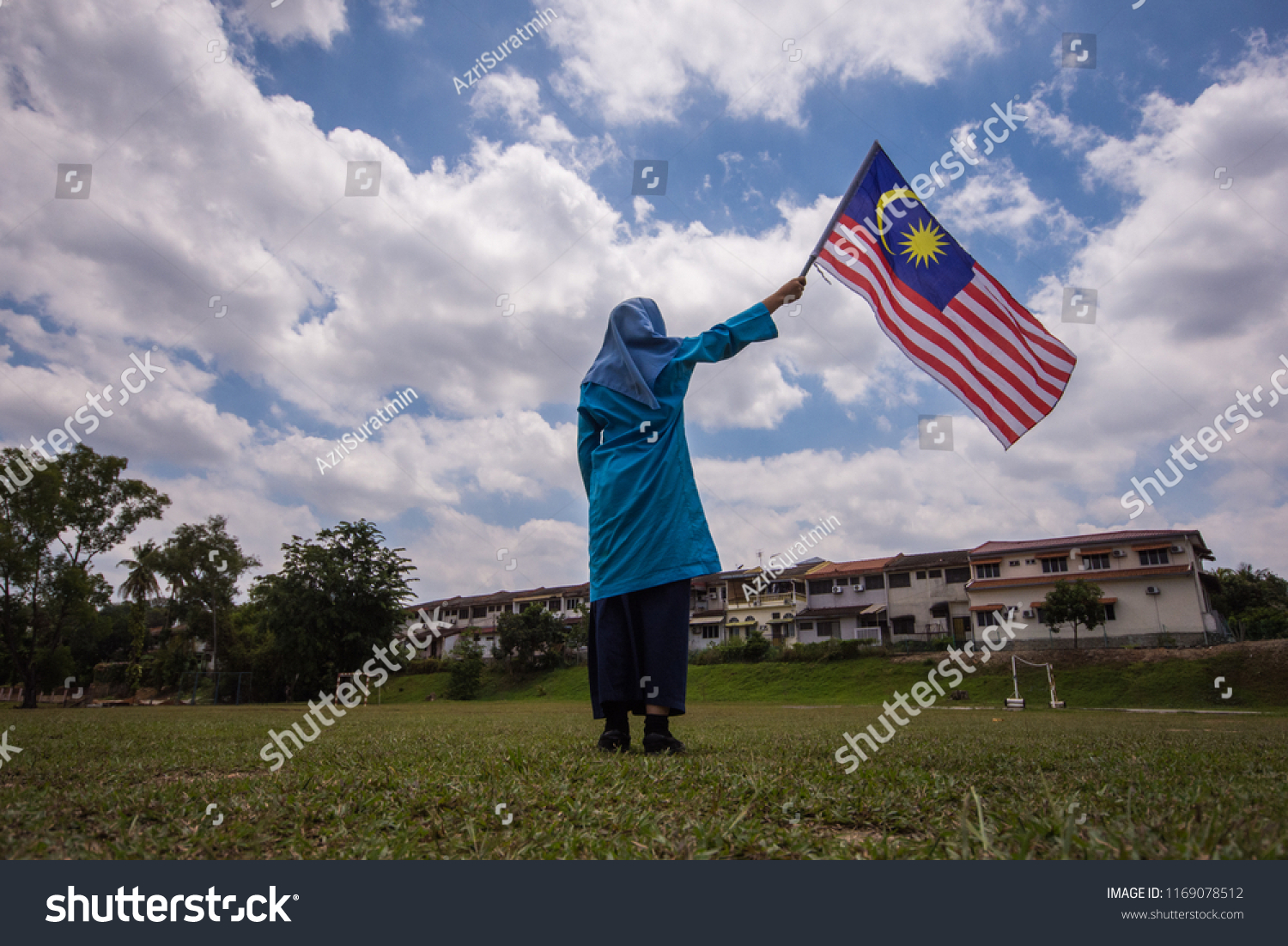 Girl waving the Malaysia Flag. Independence Day & Merdeka Concept. Blue sky and copy space. #1169078512