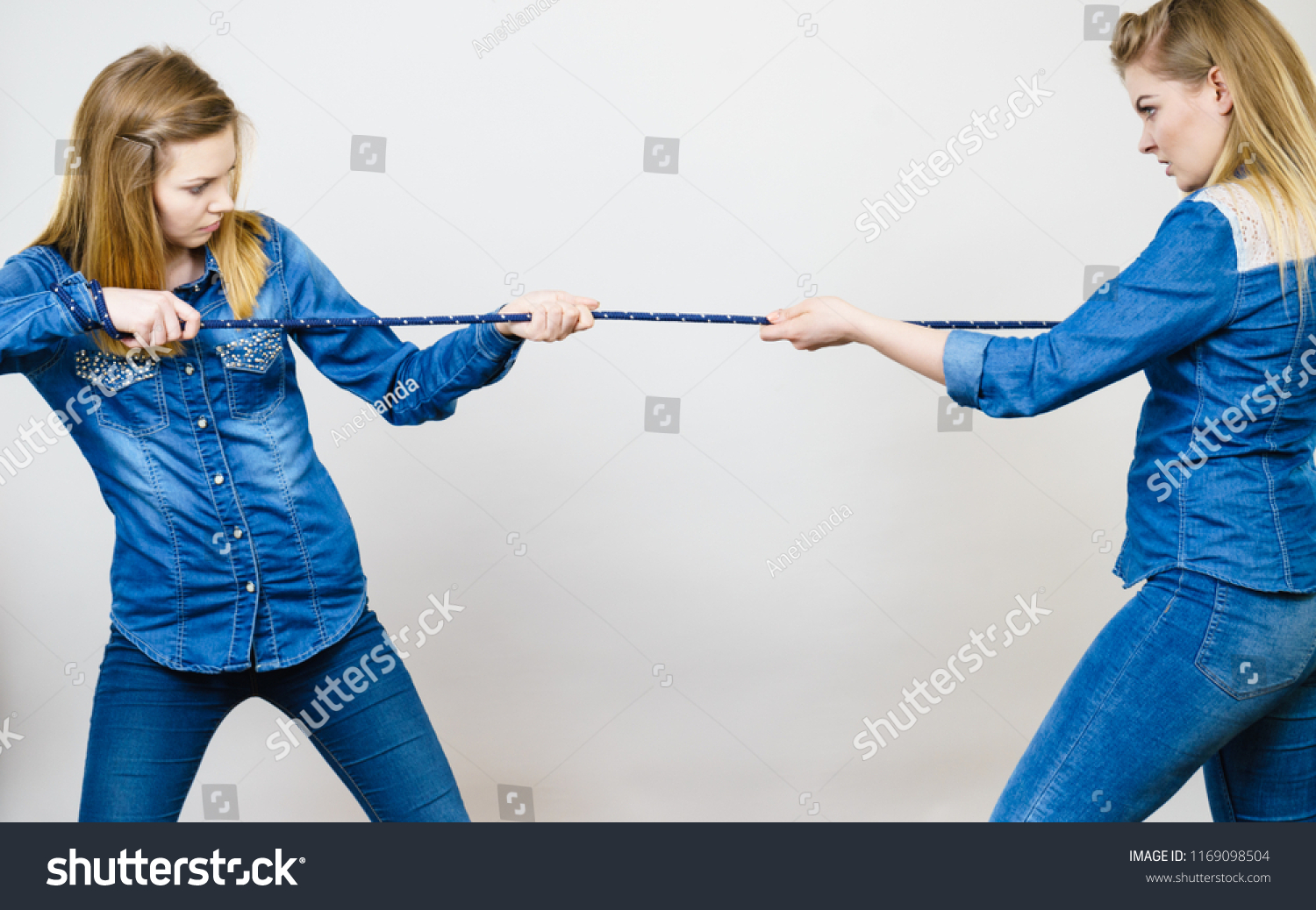 Two women having argue pulling rope being mad at each other. Bad rivalry relationship. #1169098504