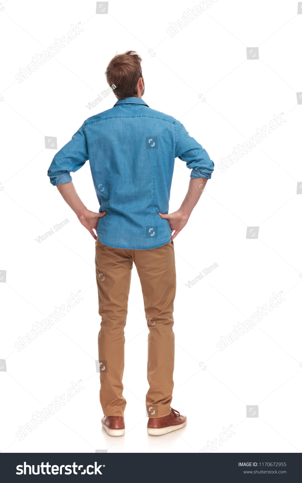 back view of a casual man with hands on waist standing and looking up on white background #1170672955