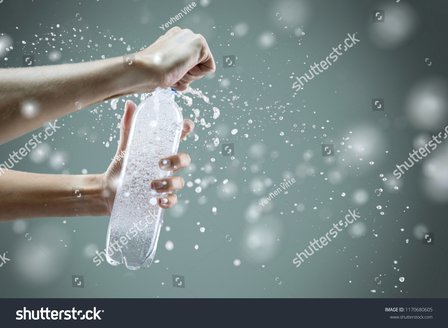 Woman's hand opening a bottle with sparkling water with splashes and lot of drops on gray background. Studio photo shooting. Concept of health lifestyle #1170680605
