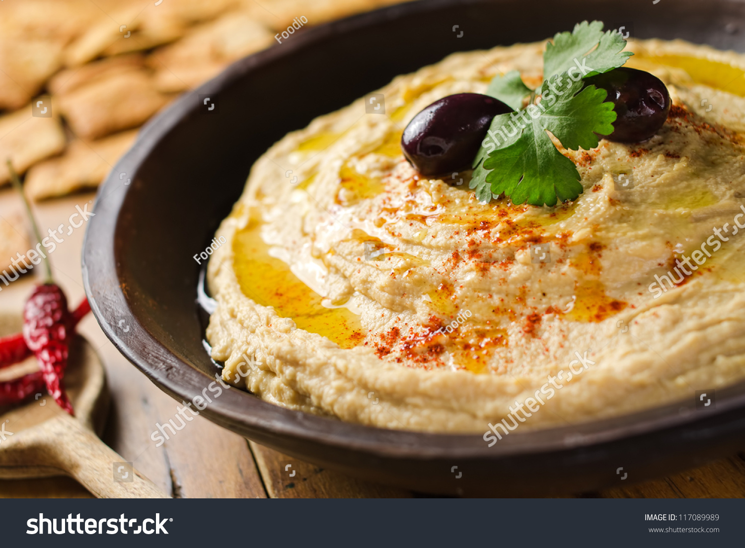 A bowl of creamy hummus with olive oil and pita chips. #117089989