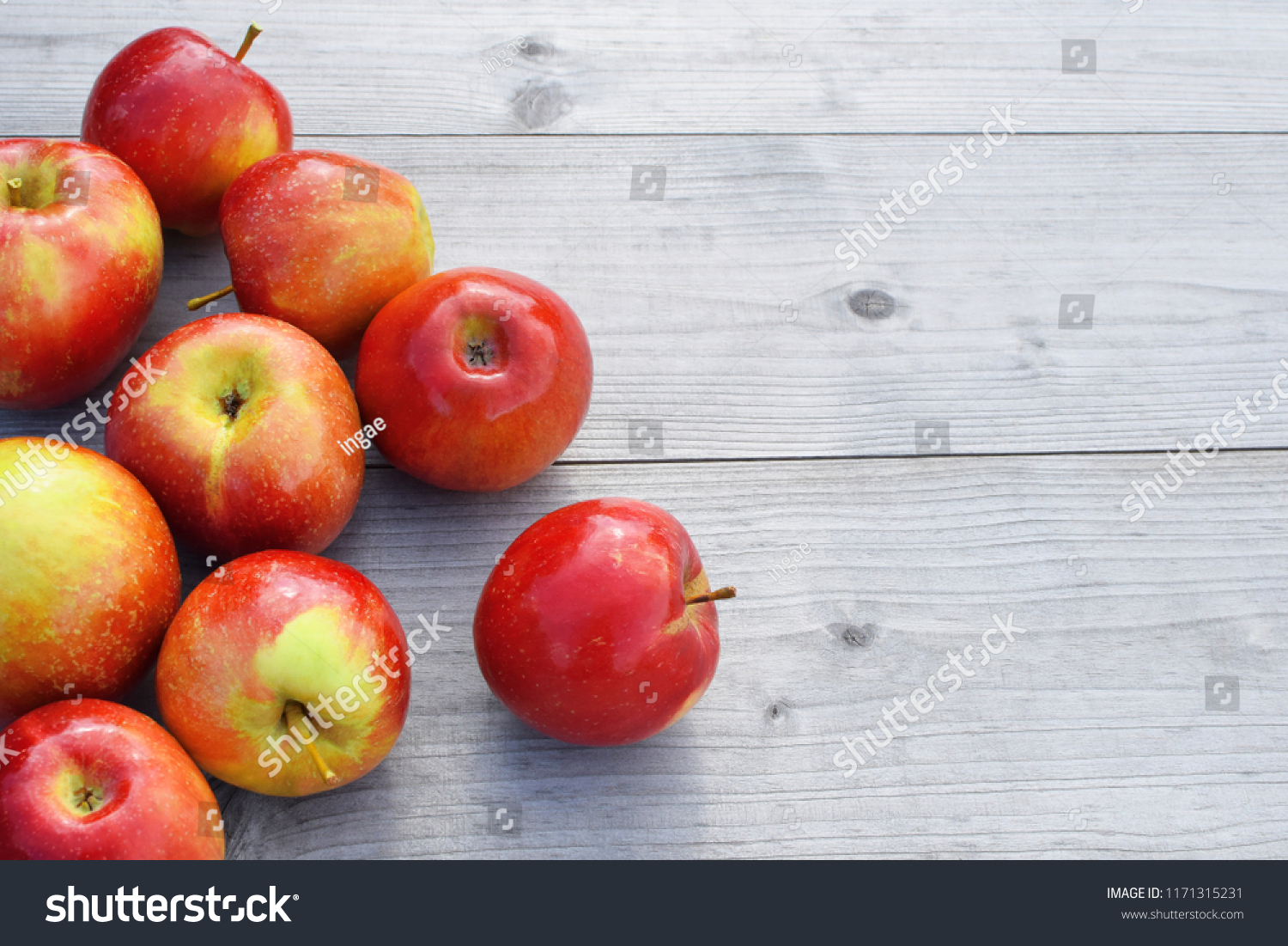 Red fresh shiny apples on grey weathered wooden table background with copy space for text. Freshly harvested sweet tasty fruit as healthy snack or prepare for delicious salad cooking or bakery.
 #1171315231