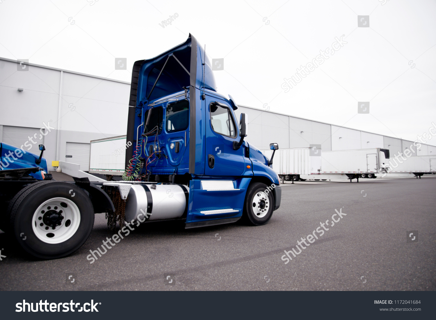 A huge number of big rig semi trucks are loaded and unloaded in the docks of huge warehouses, detaches semi trailers, attaching already loaded ones, and again the truckers kings of roads are set off #1172041684