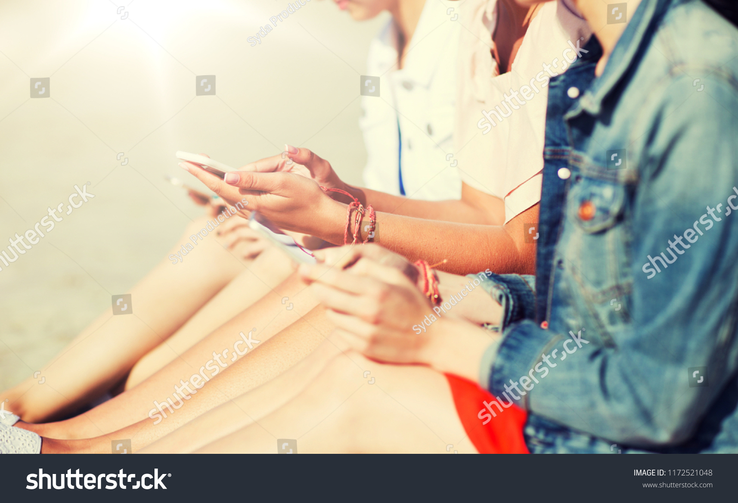 summer vacation, holidays, technology, travel and people concept - close up of young women with smartphones on beach #1172521048