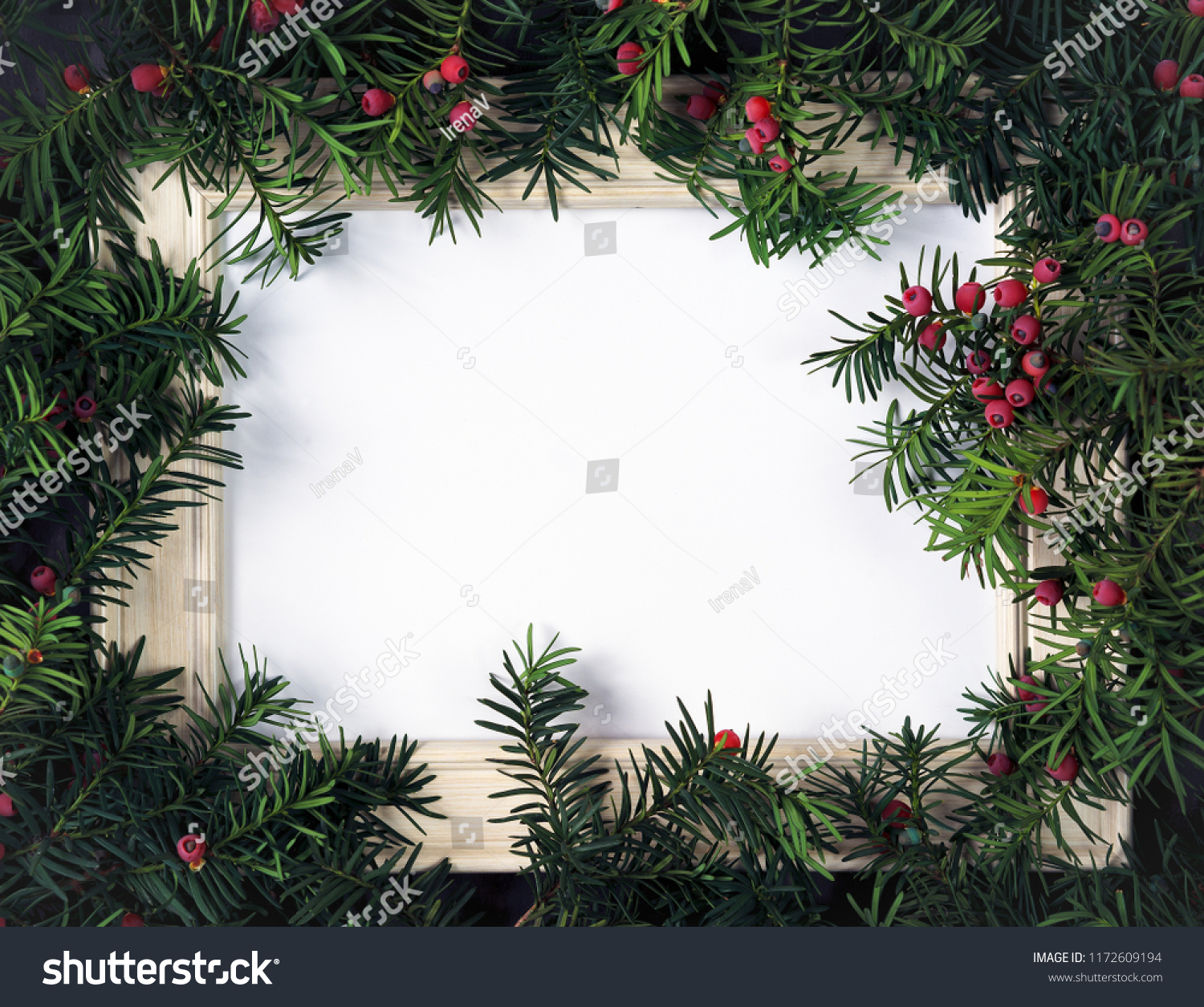 Creative layout made from Christmas tree branches with red berries and frame paper card note. Copy space for text. Nature New Year concept. Flat lay. #1172609194