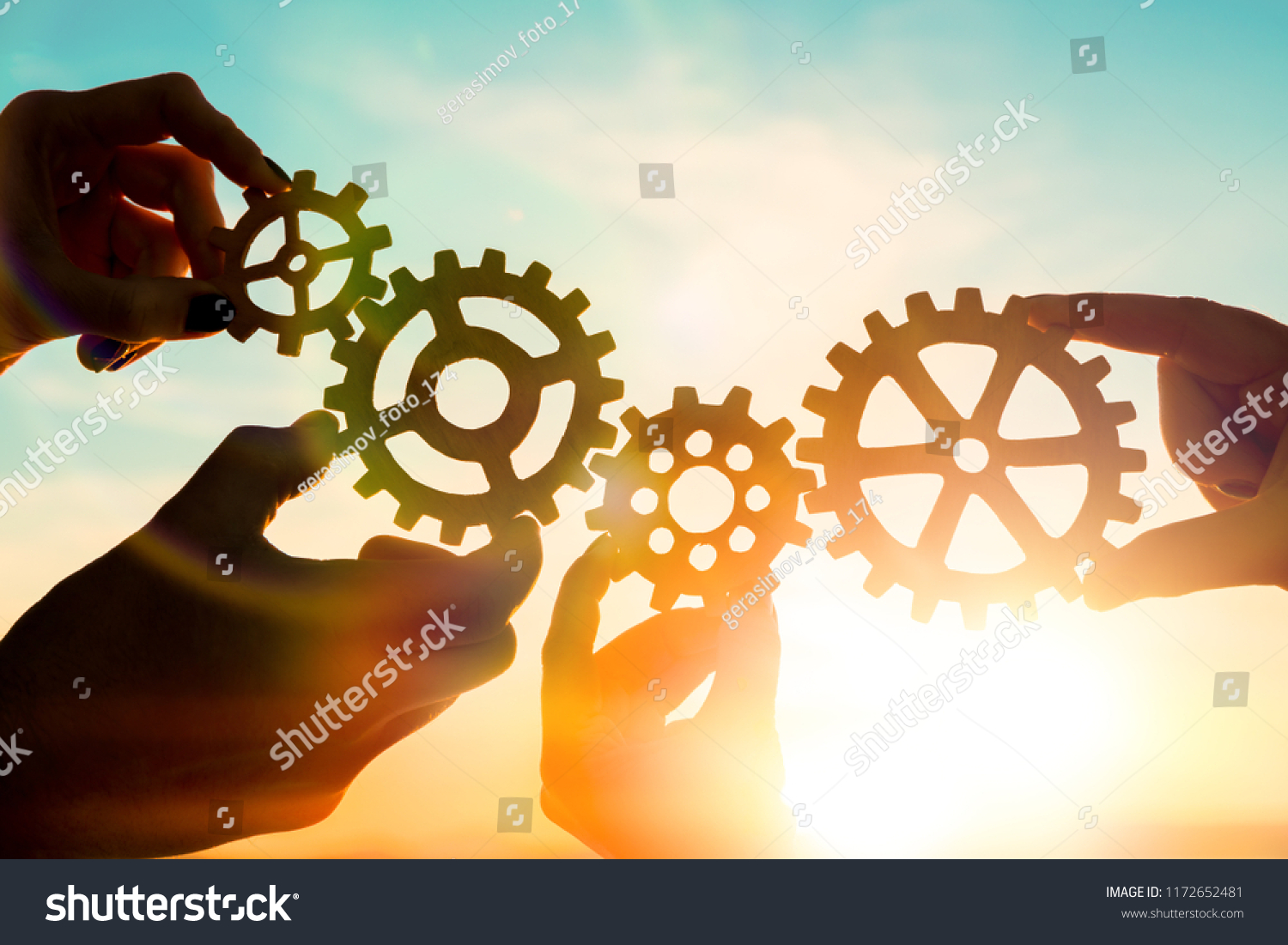 Four hands of businessmen collect gear from the gears of the details of puzzles. against the sunset. The concept of a business idea. Teamwork, strategy, cooperation, innovation. #1172652481