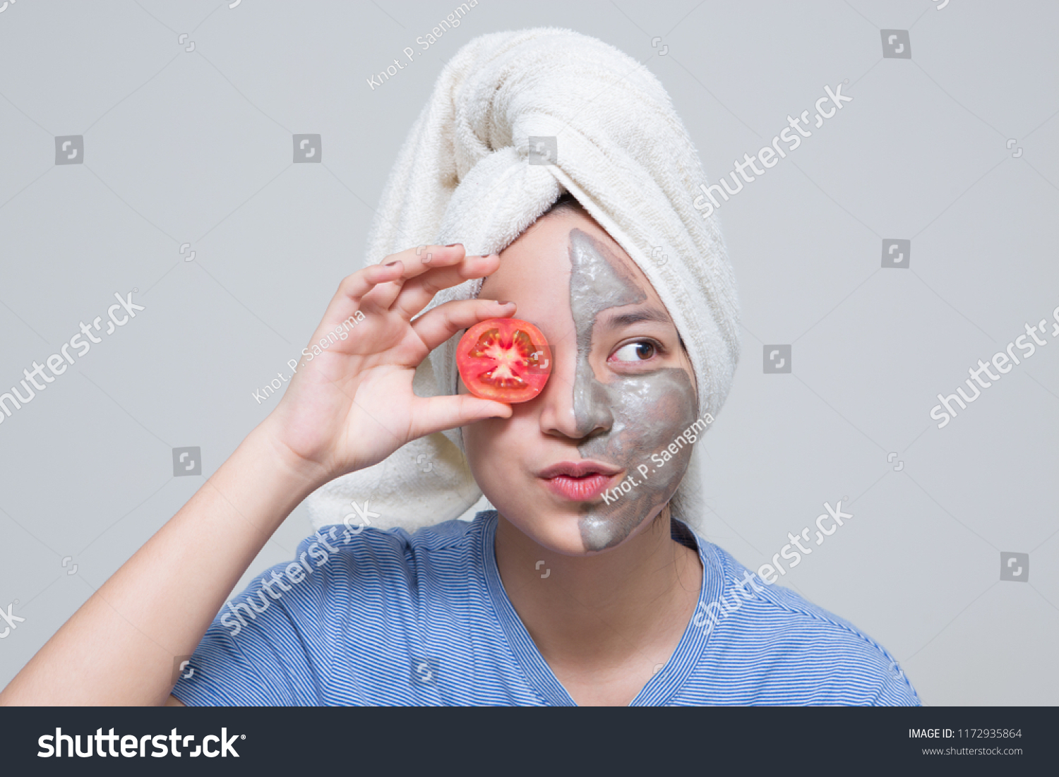 Beauty shot of Asian cute girl with beautiful skin shows mask cream on her face and holding tomato or cucumber as nutrient for treatment her facial skin #1172935864