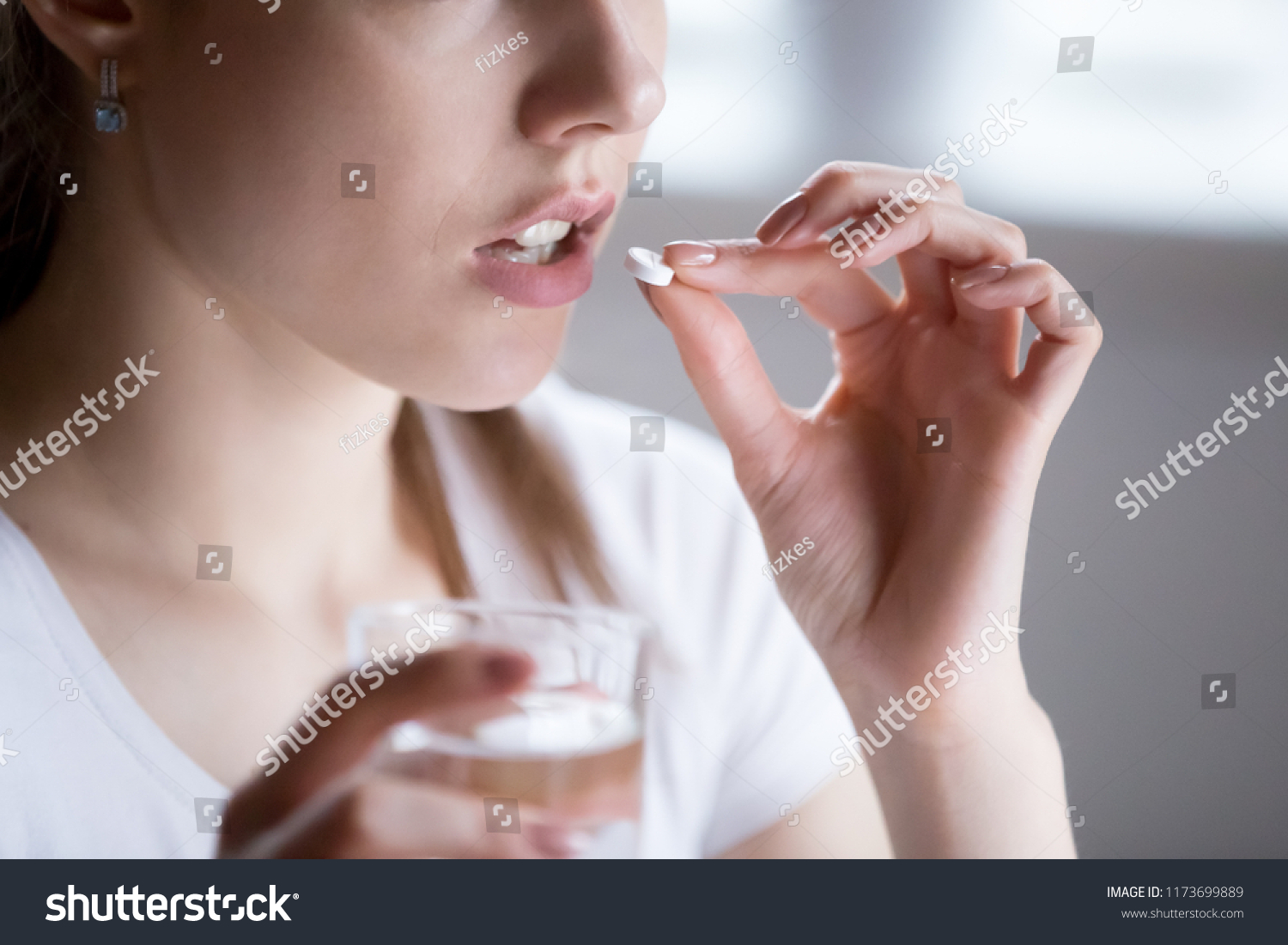 Close up of unhealthy woman feel unwell taking pill from headache or pain, female have painkiller or antibiotic medicine, girl hold glass of water and antidepressant suffering from depression #1173699889