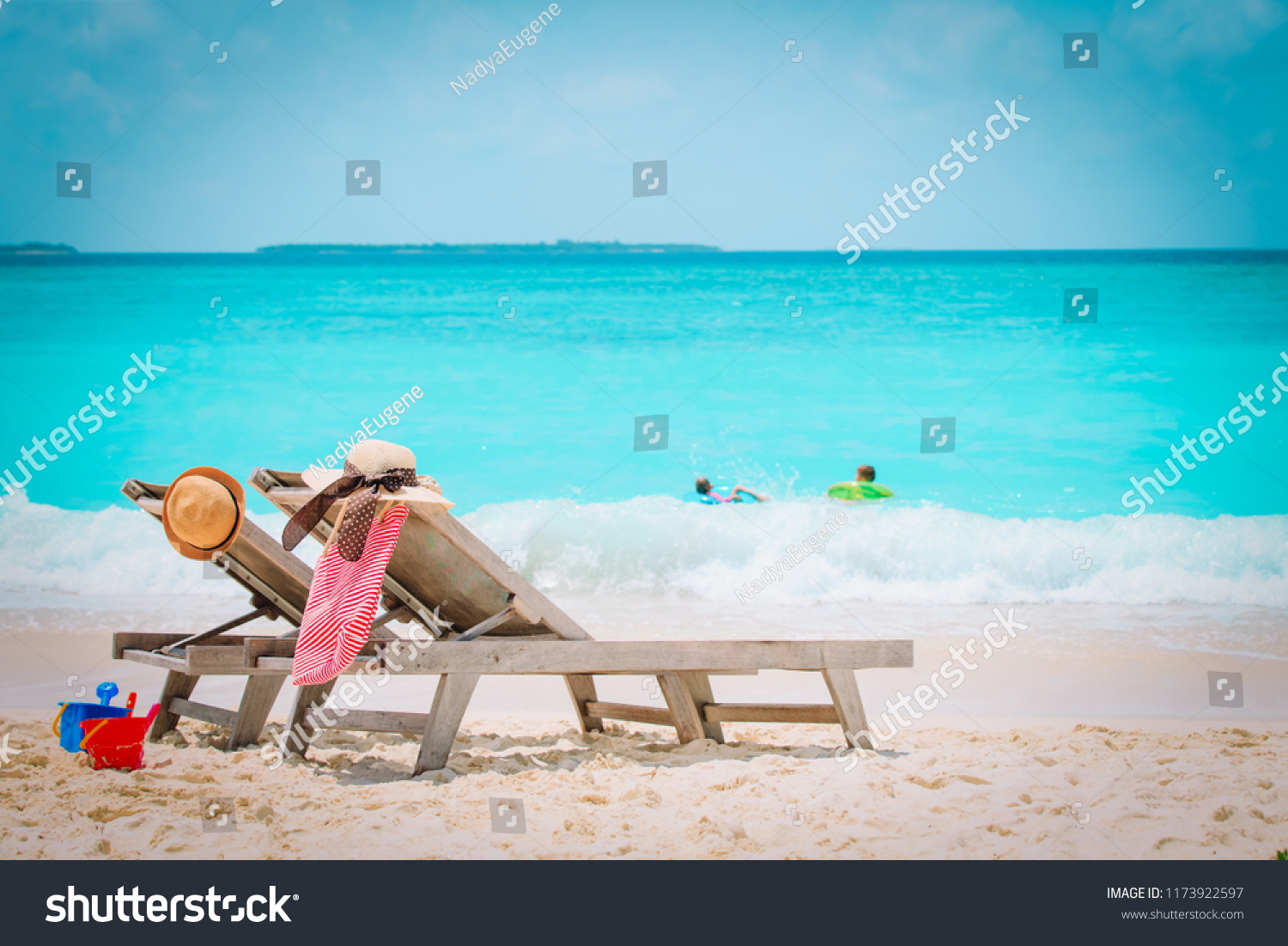 family beach vacation- chairs and kids play at sea #1173922597