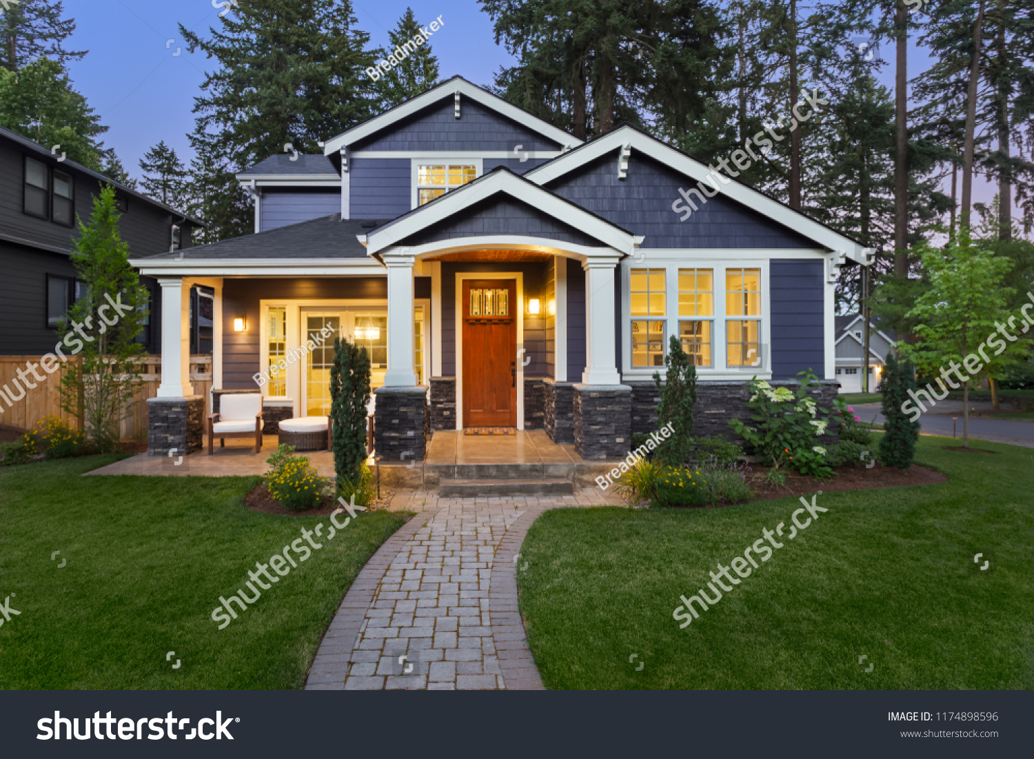 Luxury Home Exterior at Night: Beautiful New House with Green Grass and Landscaping at Twilight.Has Covered Porch and Glowing Interior Lights.  #1174898596