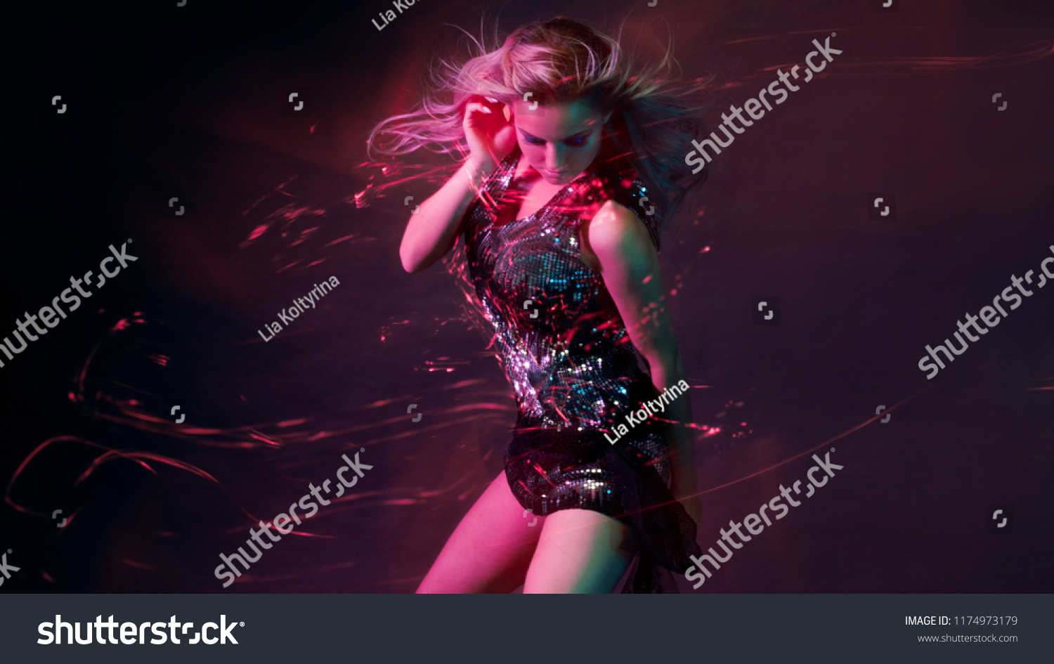 Bright and stylish young woman dancing in club, color light, motion effects. Black background, long exposure #1174973179