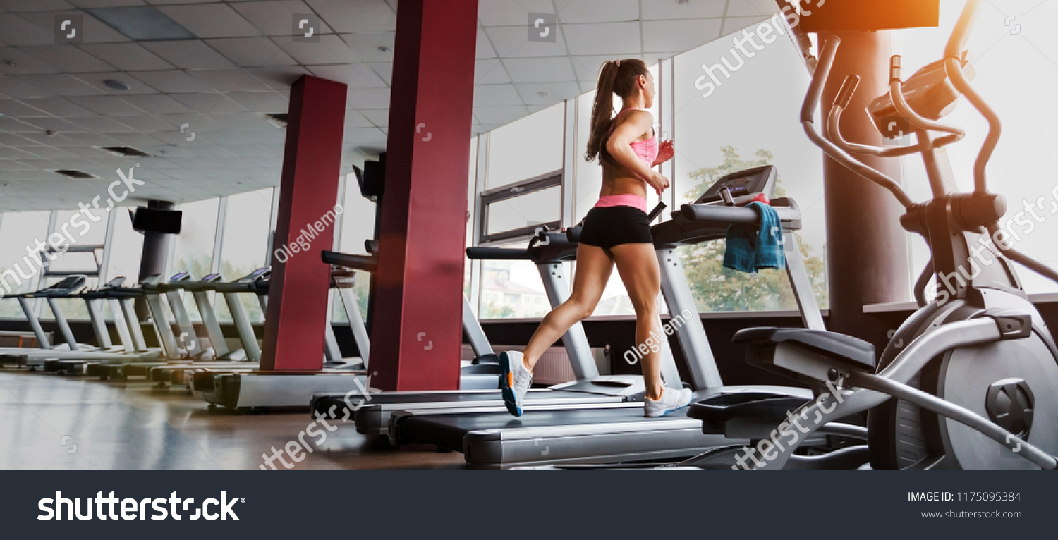 slim beautiful sporty woman running at the treadmill in the gym. Concept of cardio exercises and healthy way of life #1175095384
