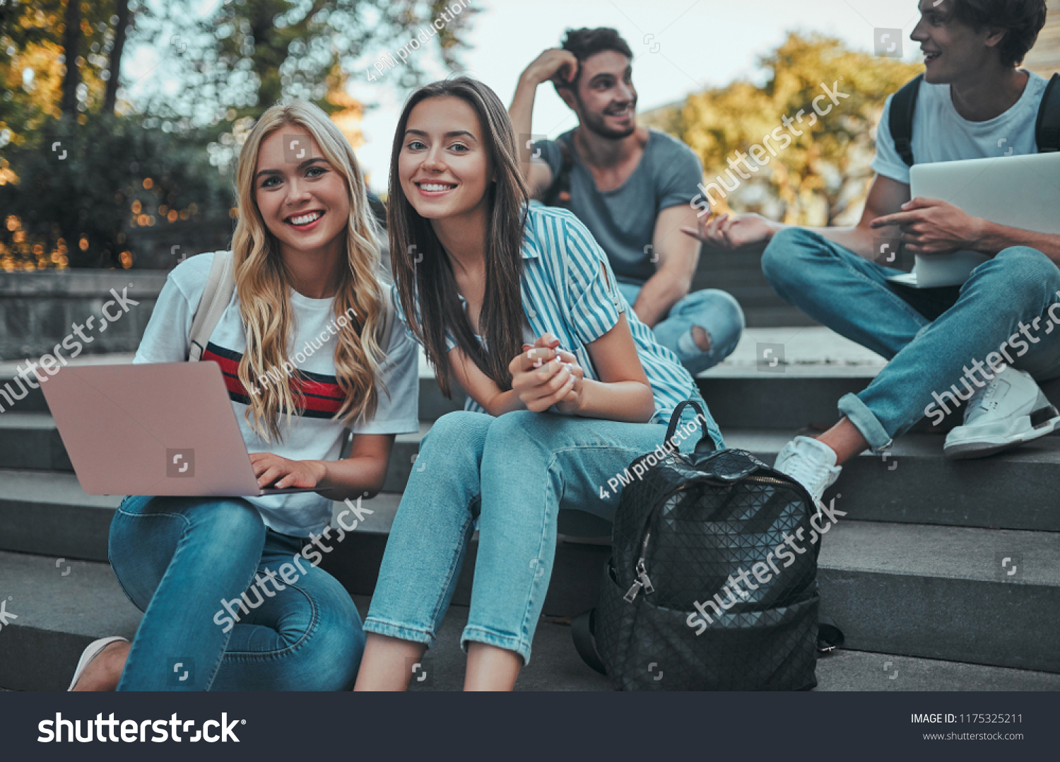 Group of young people are studying together in university. Students outdoors sitting on stairs. #1175325211