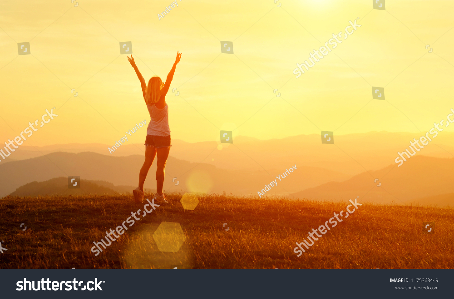 Happy woman with open arms stay on the peak of the mountain cliff edge under sunset light sky enjoying the success, freedom and bright future. #1175363449