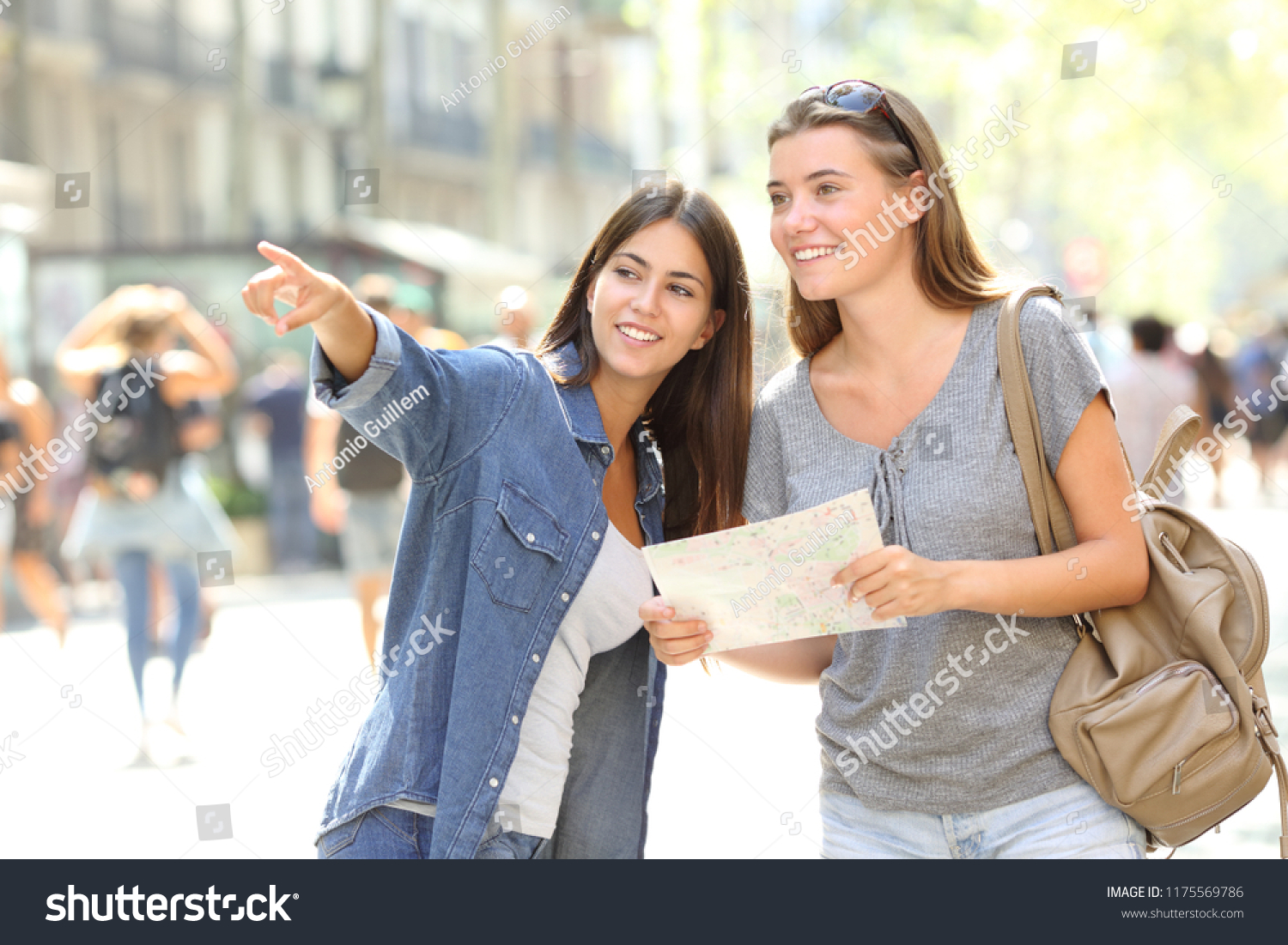 Happy girl helping to a tourist who asks direction in the street #1175569786
