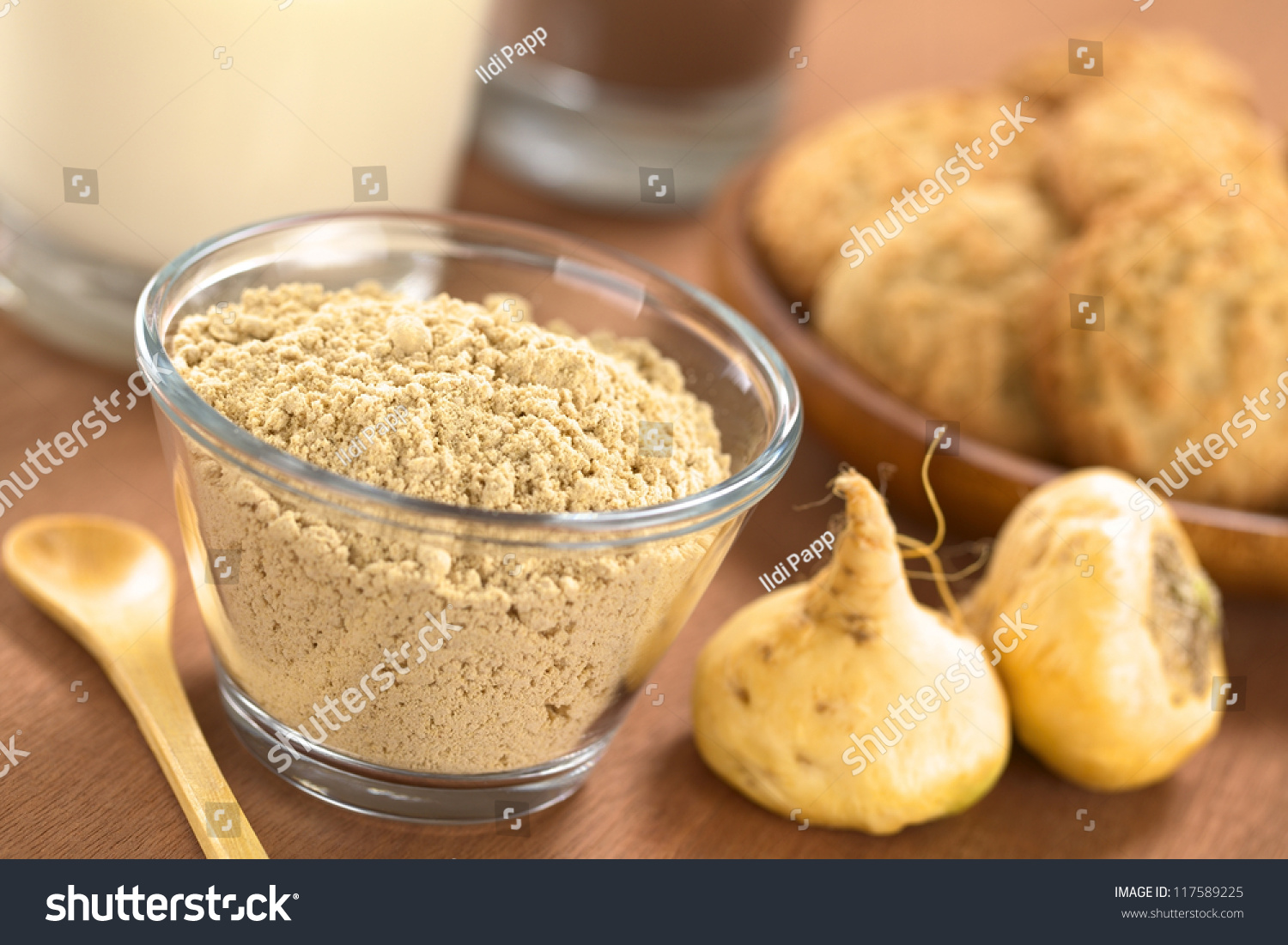 Powdered Maca or Peruvian ginseng (lat. Lepidium meyenii) in glass bowl with milk, chocolate drink, maca cookies and maca roots (Selective Focus, Focus one third into the maca powder) #117589225