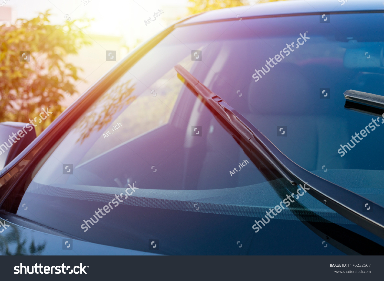 Brushes on the car glass with copy space. The work of windshield wipers - brushes and an evening sunbeam #1176232567