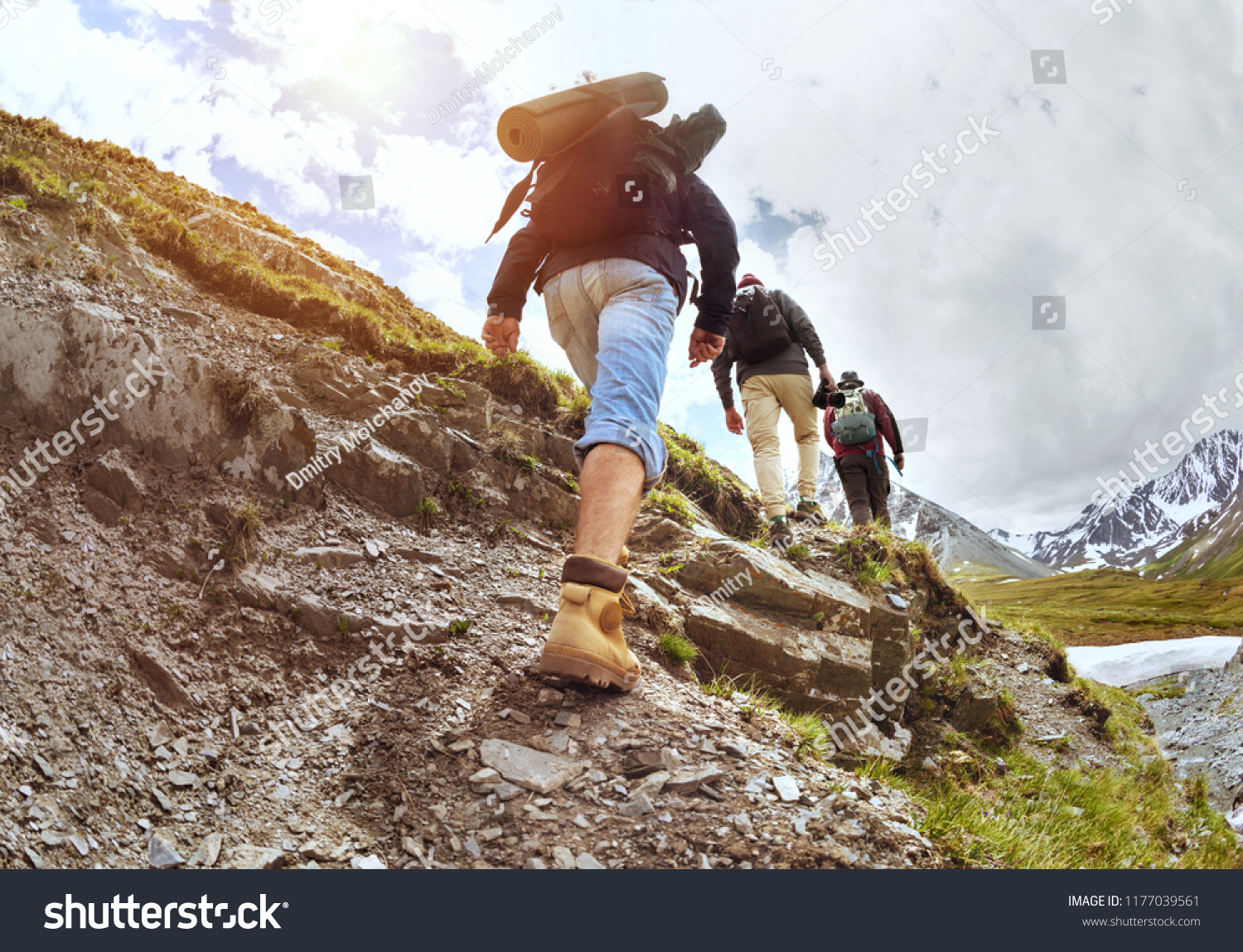Group of three tourists walking uphill by trek in mountains #1177039561