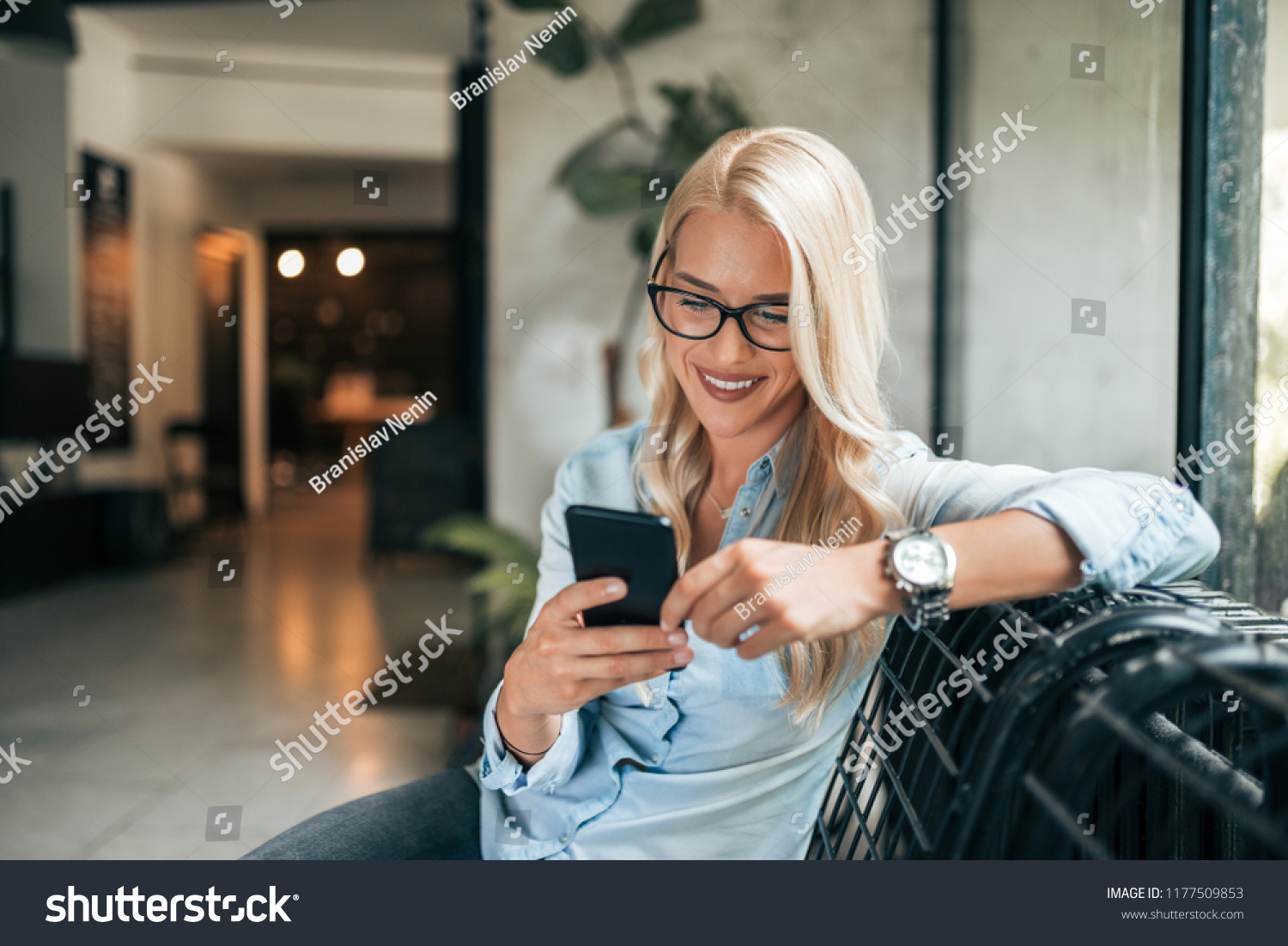 Close-up image of gorgeous blonde woman texting indoors. #1177509853