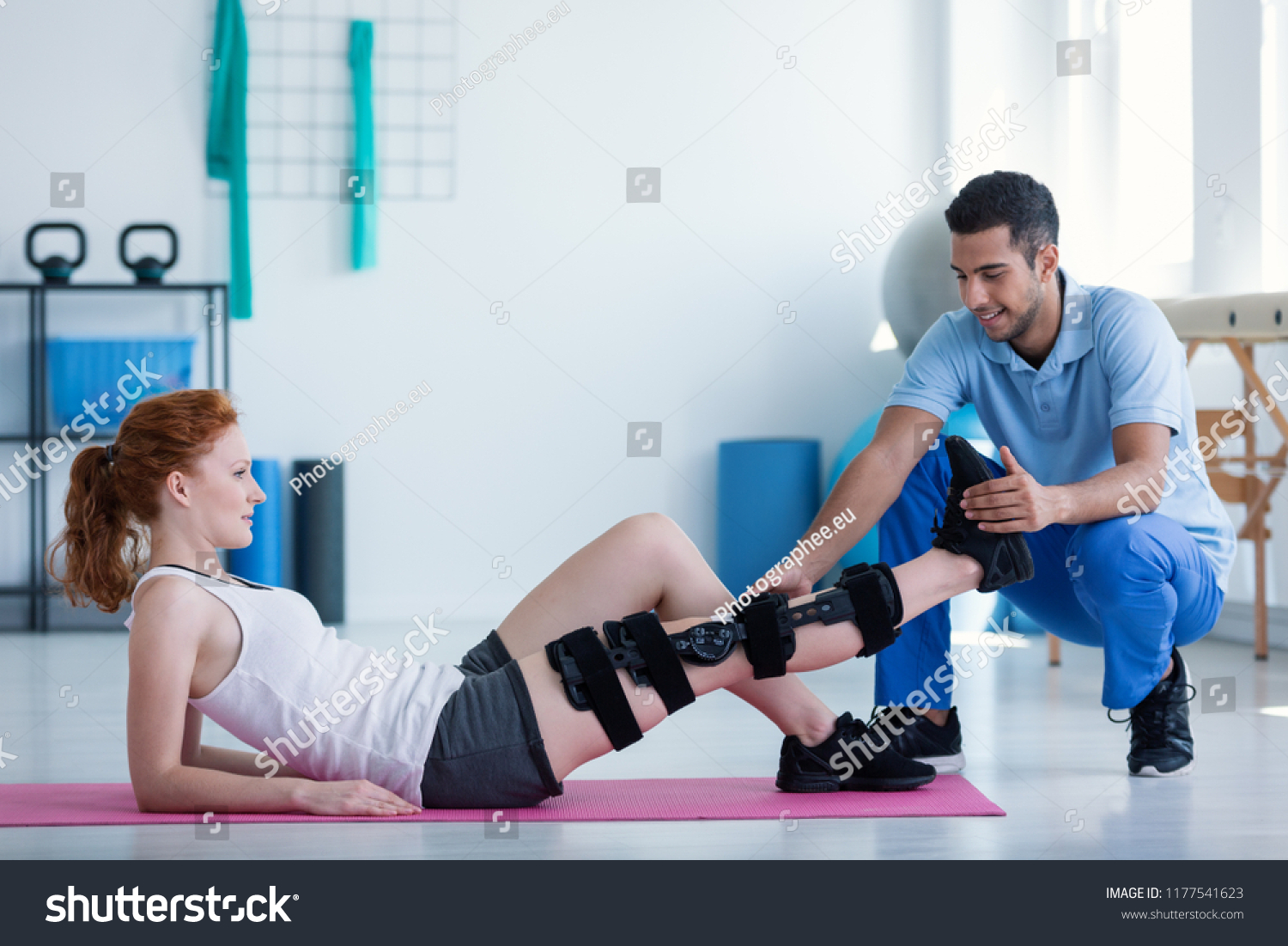 Woman with leg injury on mat and smiling doctor during treatment in the hospital #1177541623