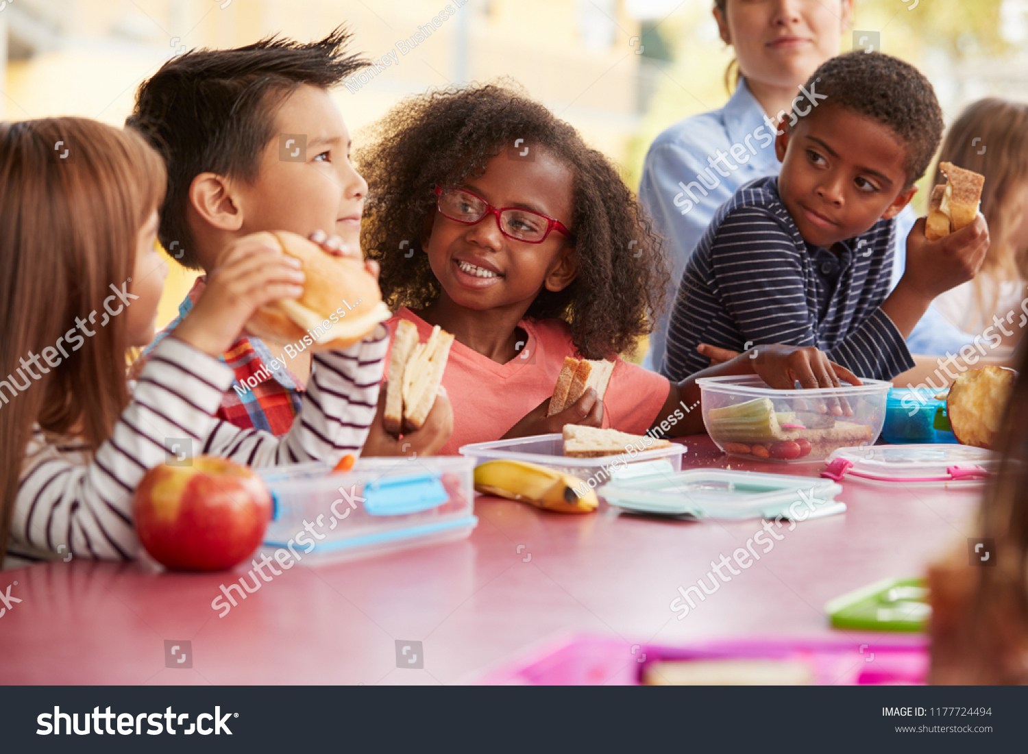Young school kids eating lunch talking at a table together #1177724494