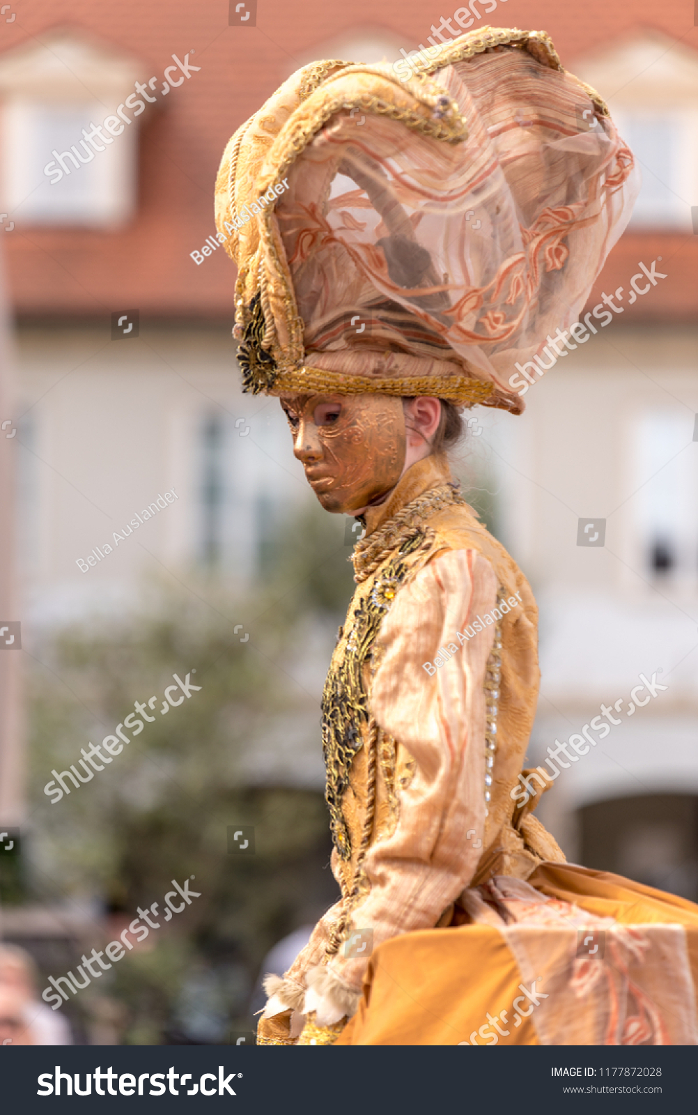 masked woman dressed in gold in Venetian carnival costume #1177872028