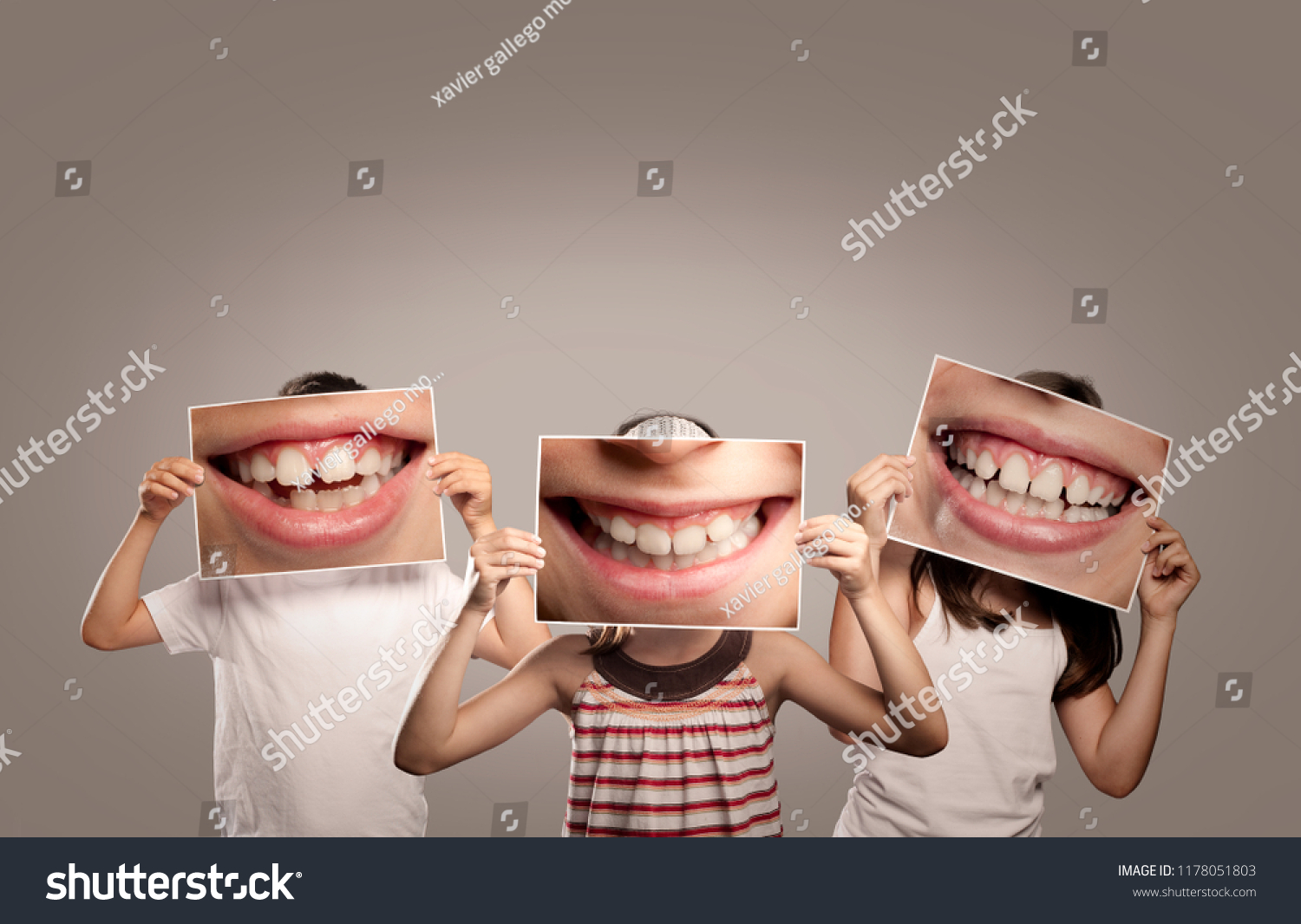 three children holding a picture of a mouth smiling #1178051803