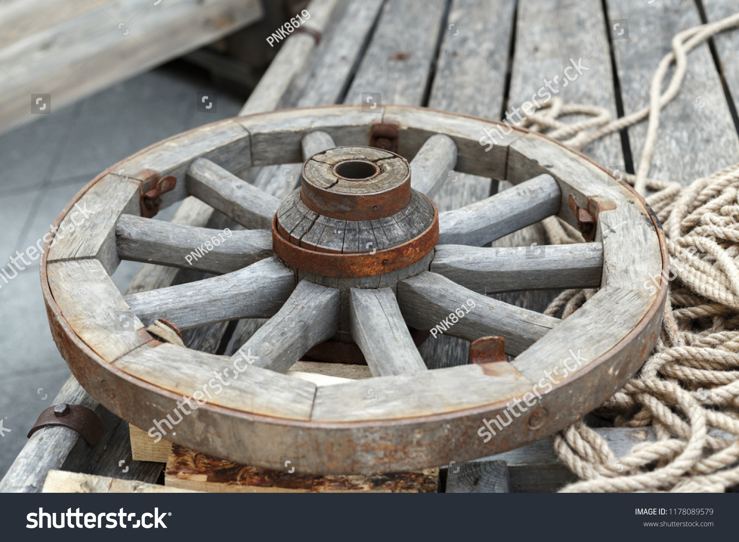 Old wooden wheel lying on a wooden cart #1178089579