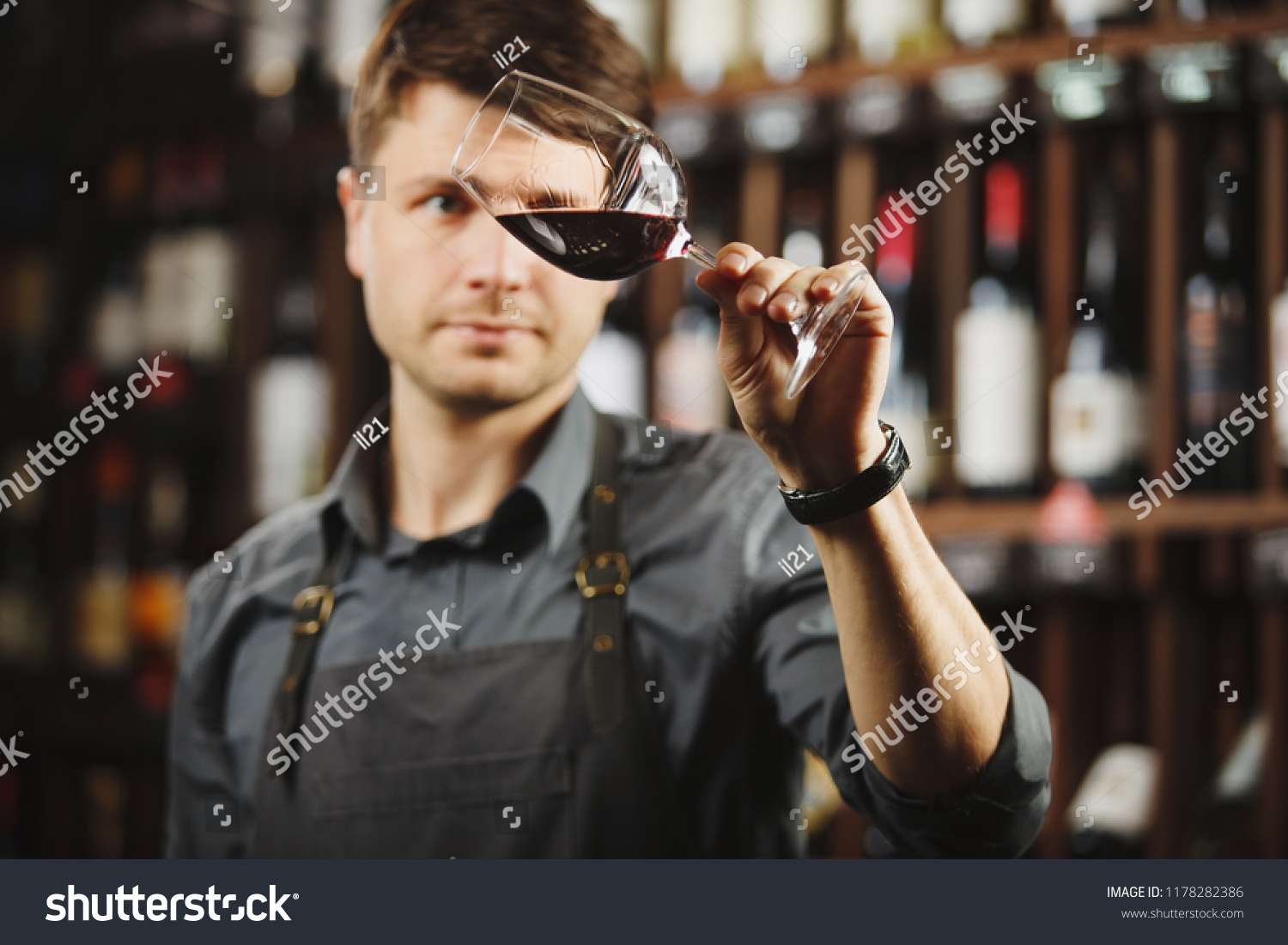 Bokal of red wine on background, male sommelier appreciating drink #1178282386
