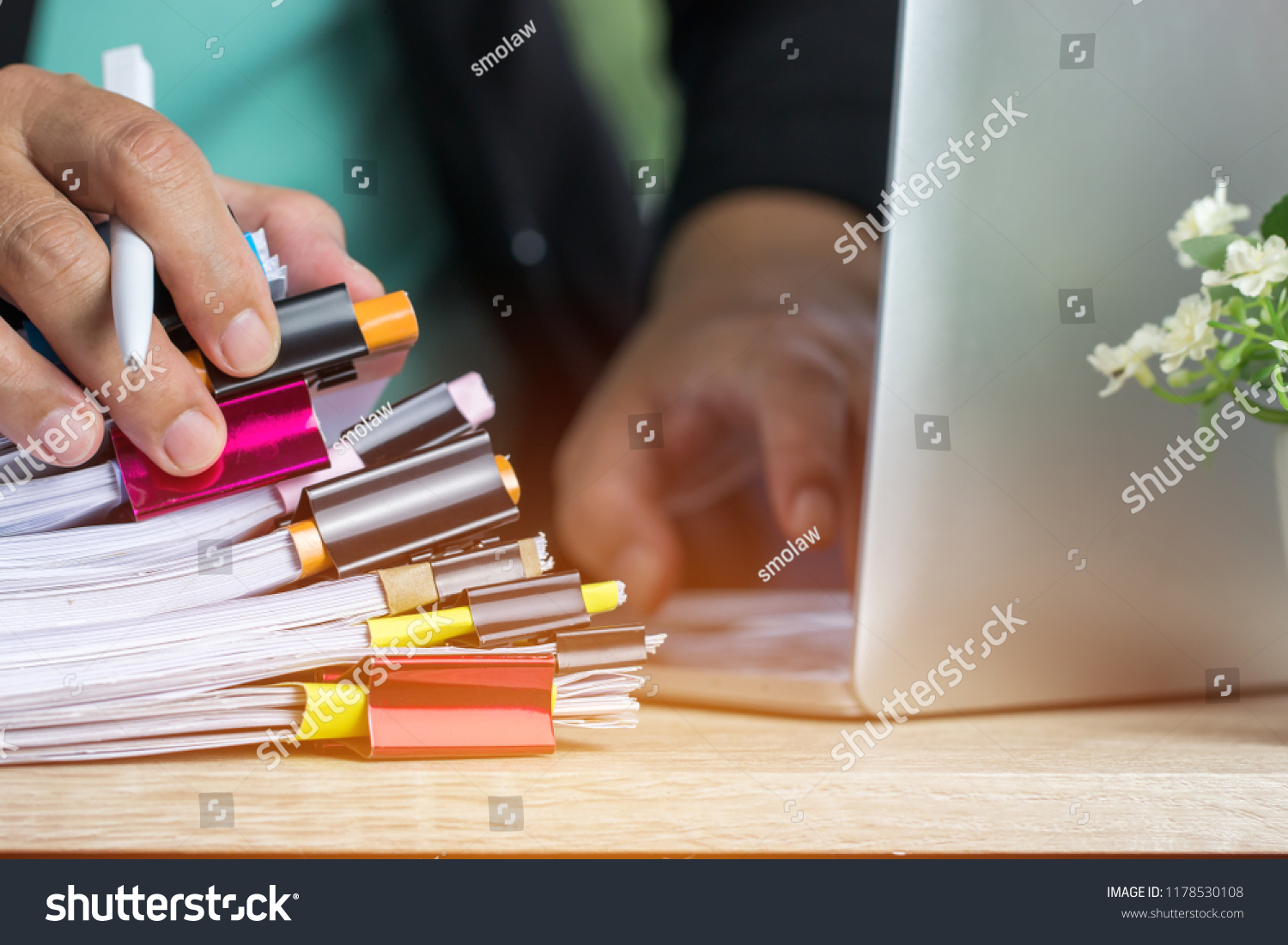Businessman hands holding pen working in Stacks of paper files searching info unfinished documents achieves with  business report papers, Professional work for financial document on computer in office #1178530108