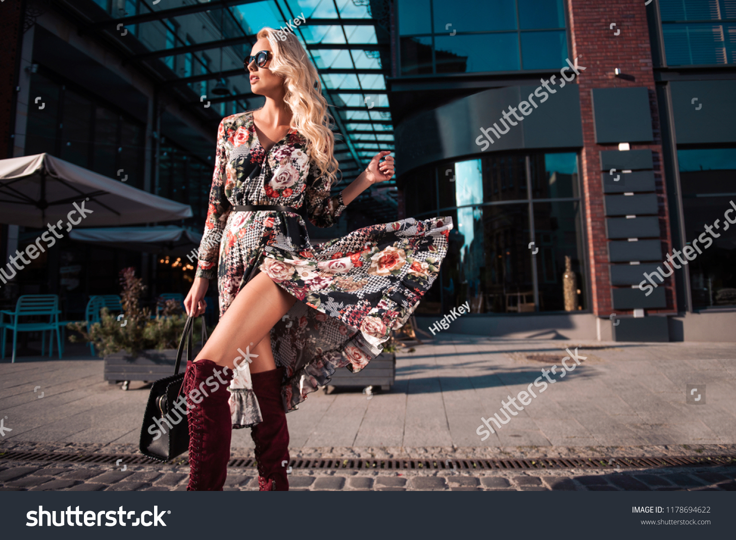 Beautiful fashionable woman walking in the street, wearing sunglasses, nice dress, high heels boots, handbag. Fashion urban autumn photo. #1178694622