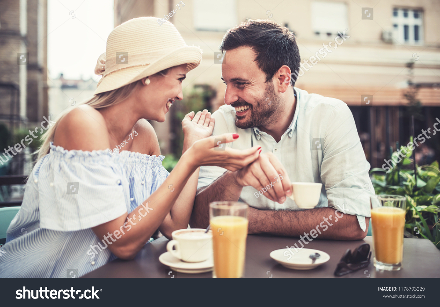 Flirting in a cafe. Beautiful loving couple sitting in a cafe drinking coffee and enjoying in conversation. Love, romance, dating #1178793229