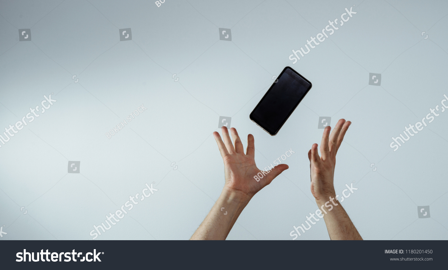 A view of the hand that tosses or catches a mobile phone. The smartphone is falling, hands are trying to catch it. The concept of communication, attempts to connect and talk. #1180201450