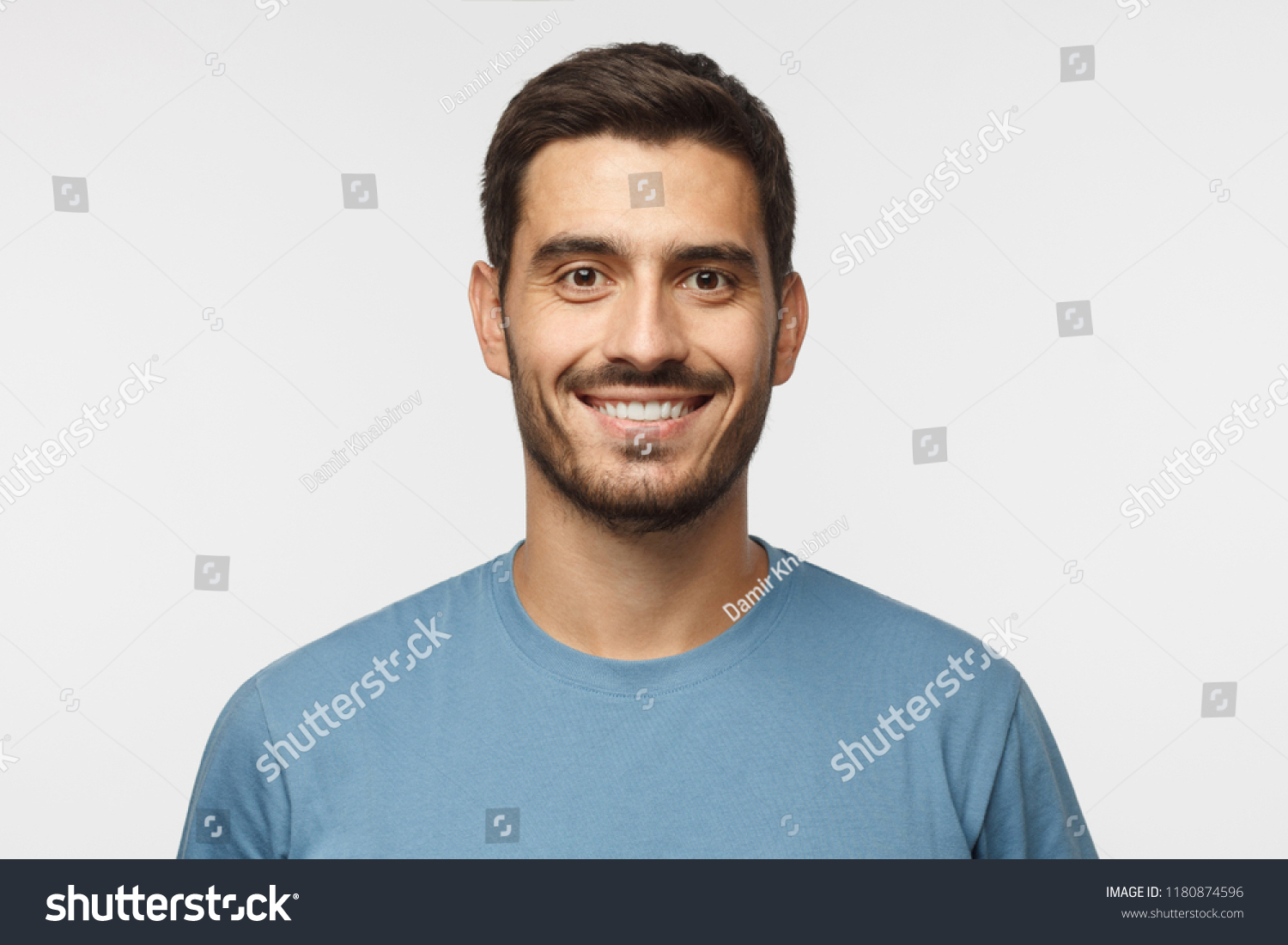 Close up portrait of young smiling handsome guy in blue t-shirt isolated on gray background #1180874596