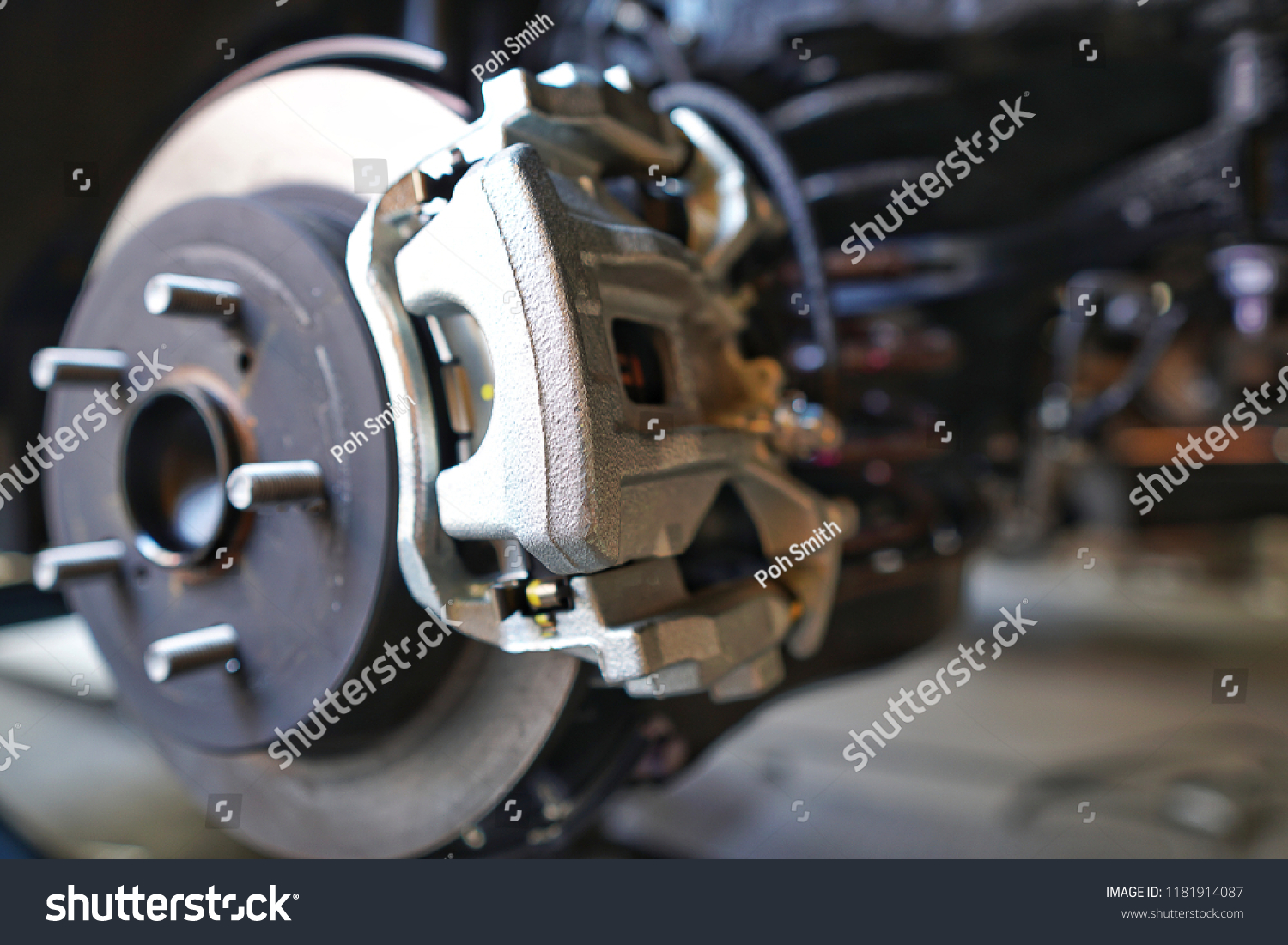 Selective focus of Brake Disc of the vehicle for repair.Automobile mechanic in process of new tire replacement.Car brake repairing in garage.Car Service and technician concept. #1181914087