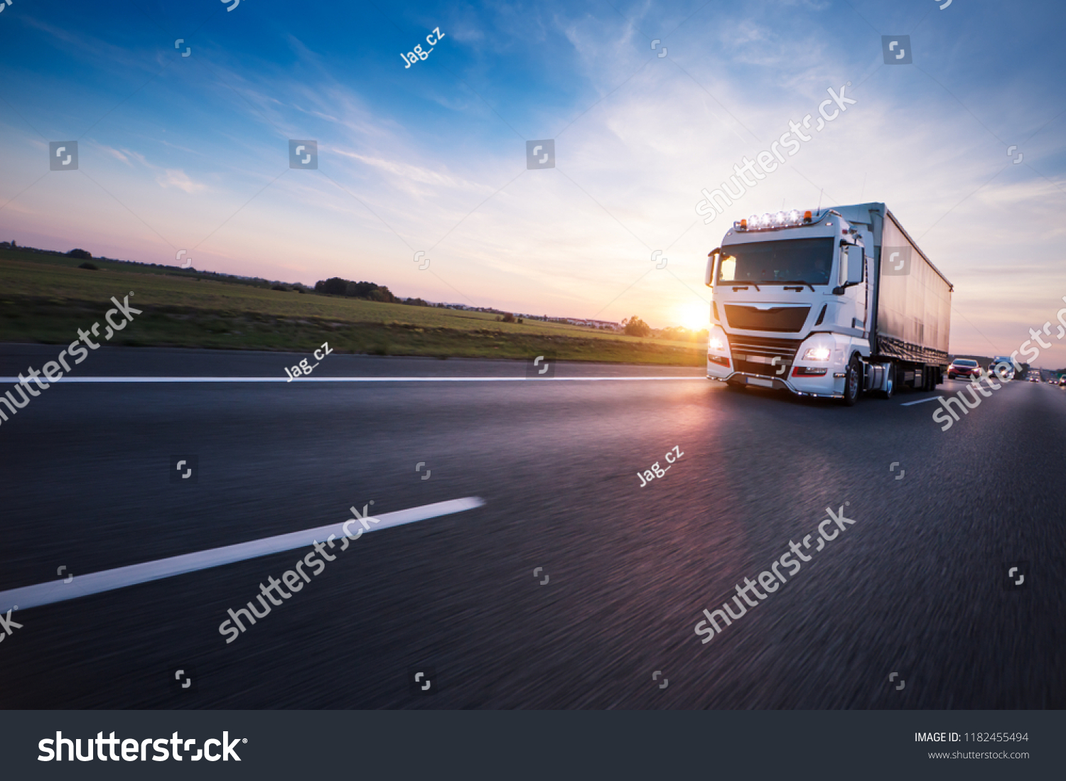 Loaded European truck on motorway in beautiful sunset light. On the road transportation and cargo. #1182455494