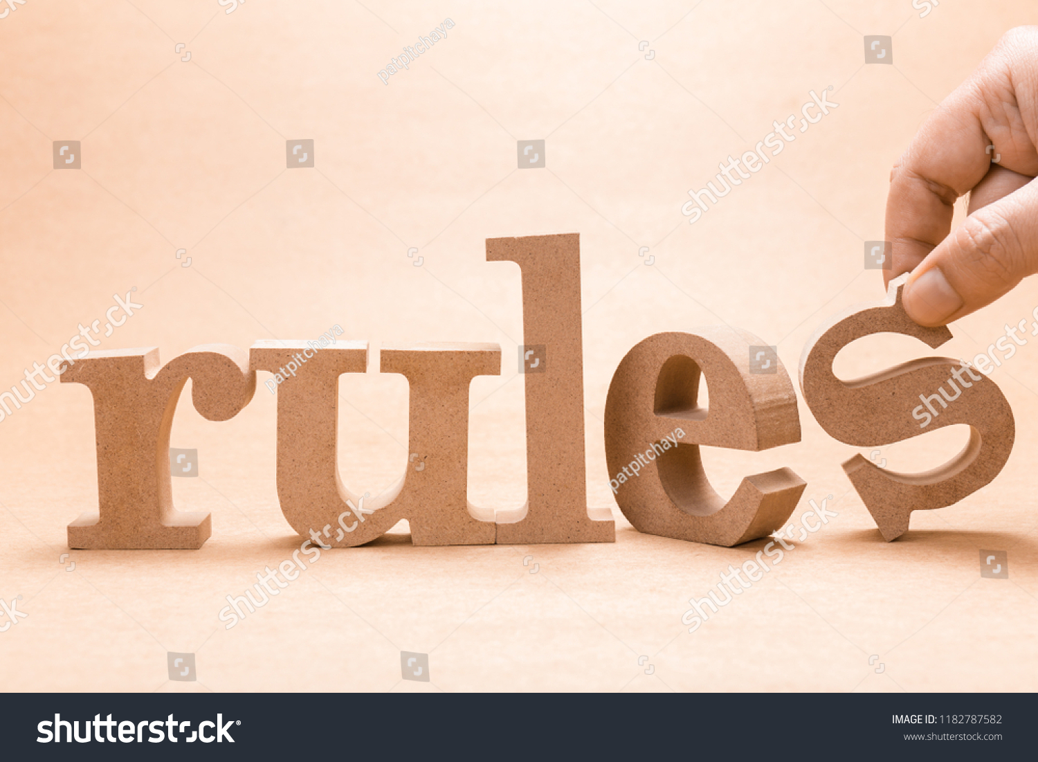 Hand arrange wood letters on brown paper as RULES word #1182787582