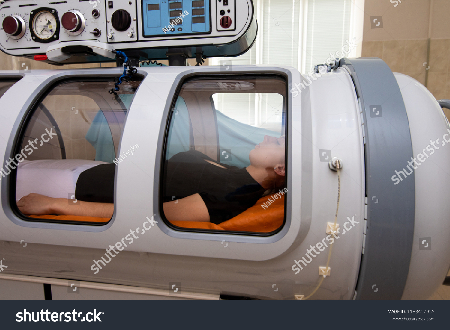 beautiful girl in a black T-shirt and white pants lies in a hyperbaric chamber #1183407955