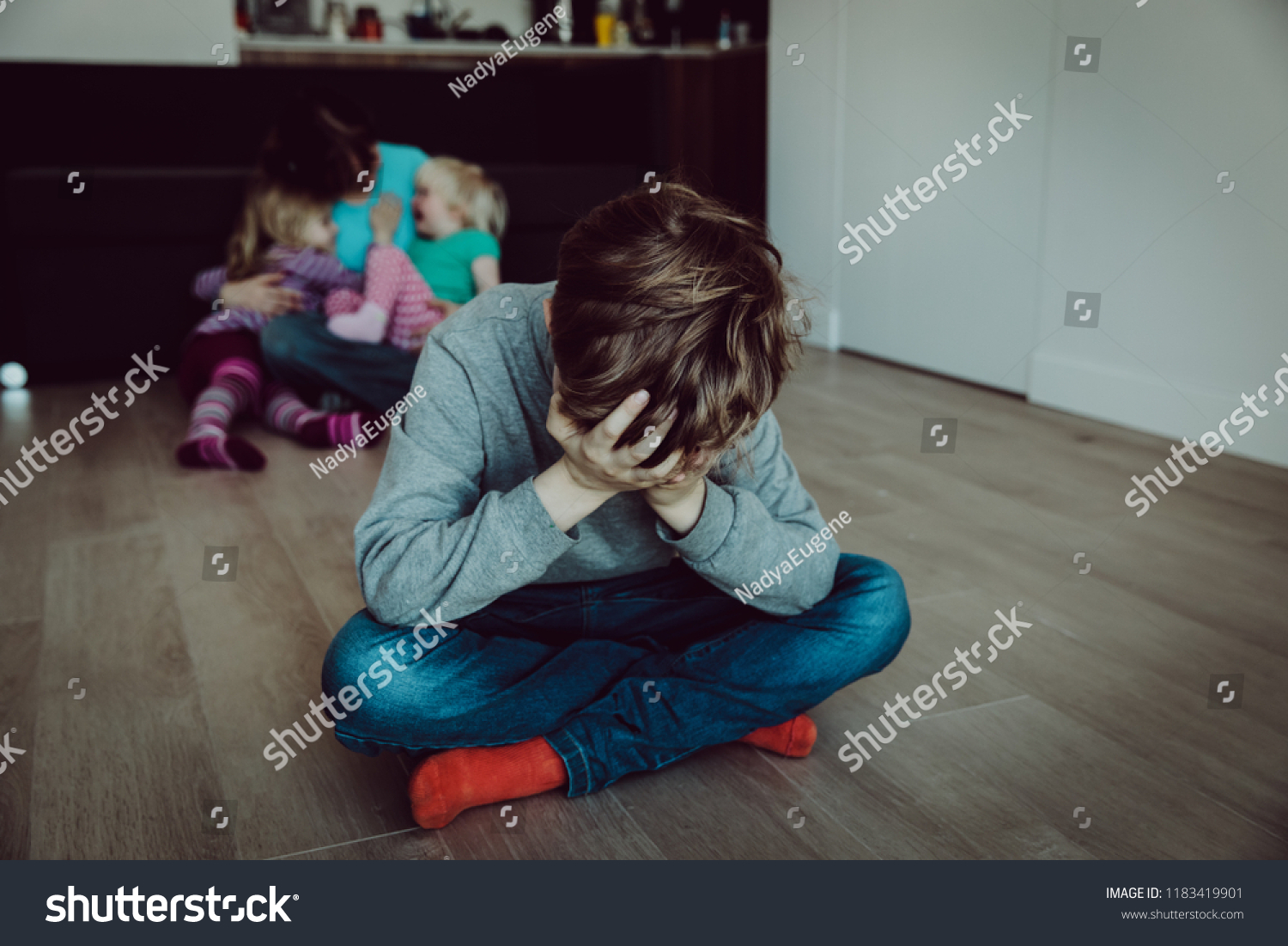 family rivalry-crying sad child and mother holding other kids #1183419901