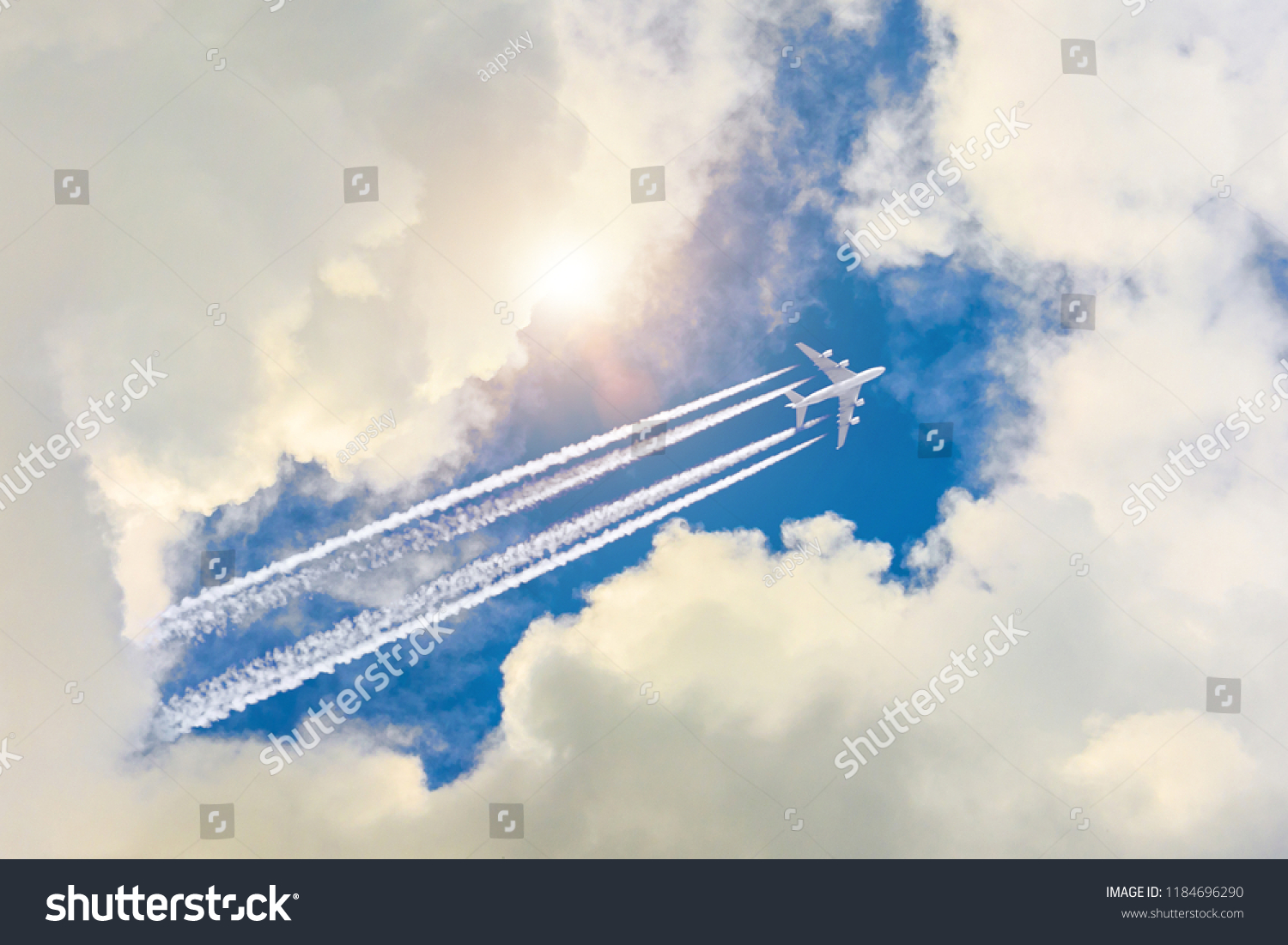 Airplane flies high in the sky, a journey through the clouds and a sunny glare #1184696290