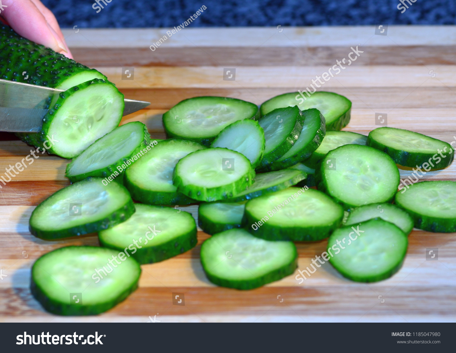 Cucumber sliced with circles lies on a wooden board, cooking, healthy food and vitamins #1185047980