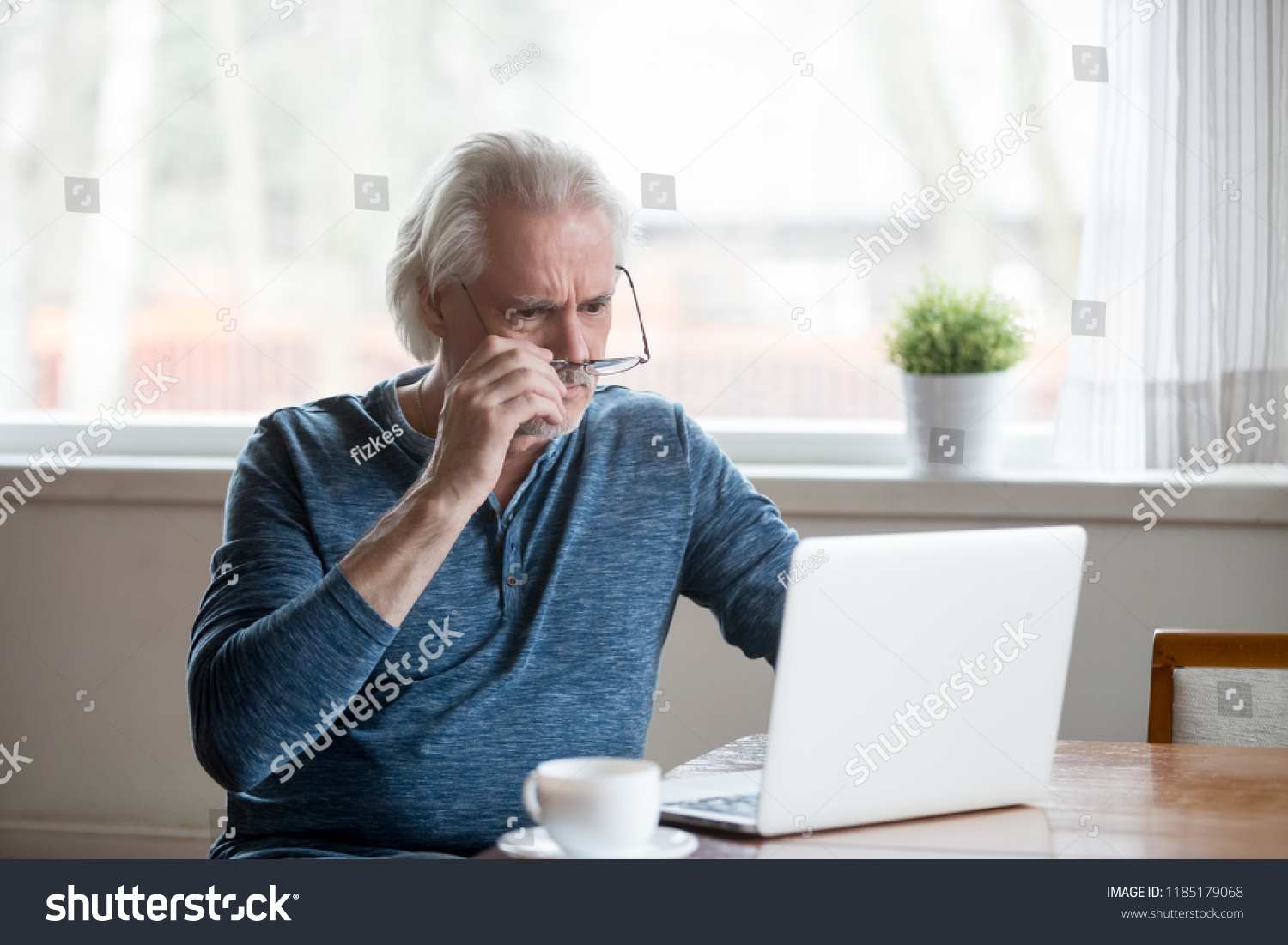 Shocked frustrated senior mature man taking off glasses to look at laptop reading shocking online news at home, stressed worried middle aged old male confused by bad email news or computer problem #1185179068