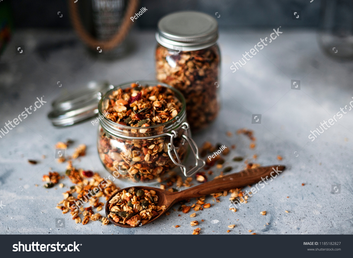 Home granola in a glass jar. Selective focus, concrete background.Healthy vegan snack #1185182827