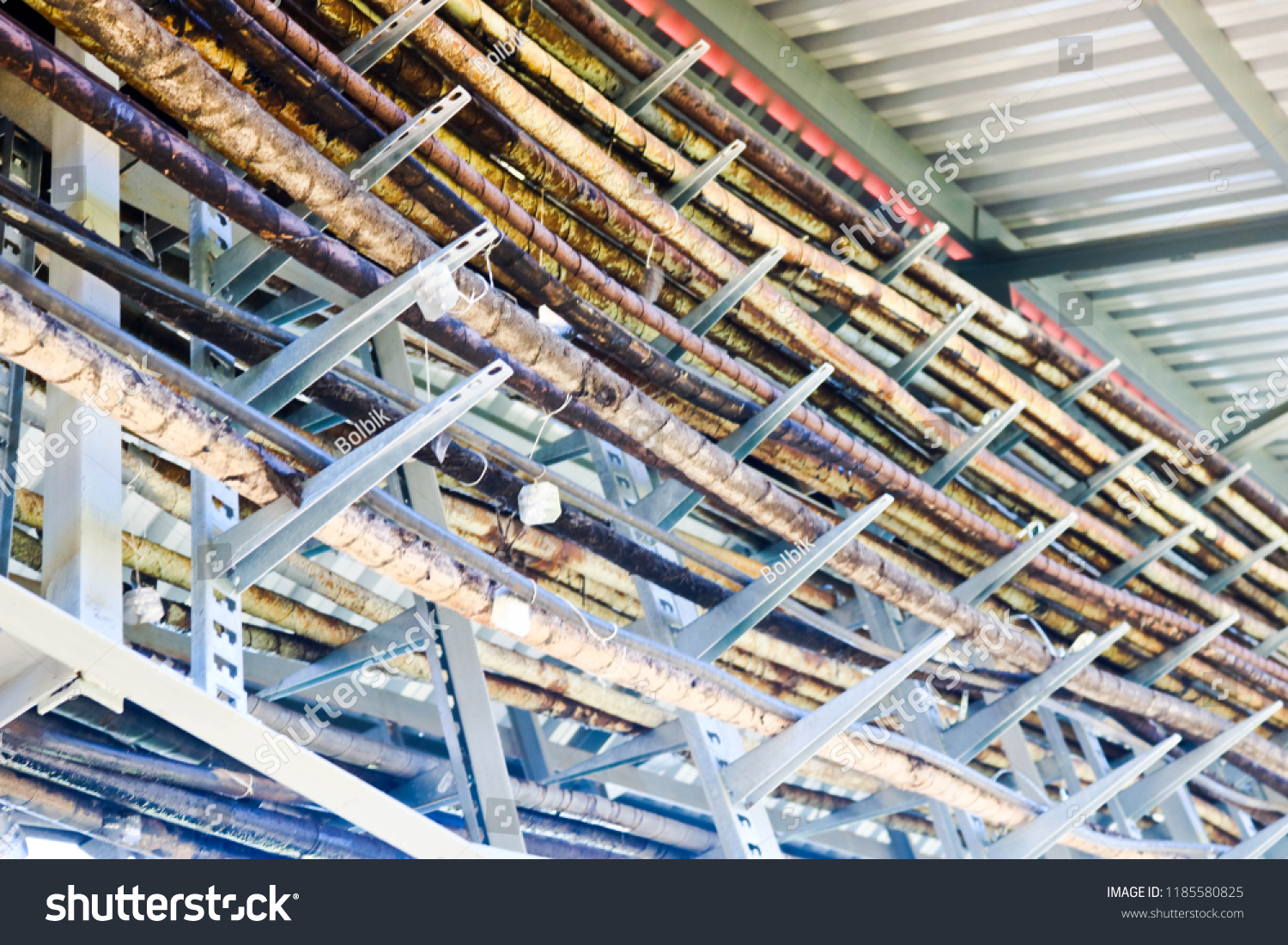 Metal wires in a bunch. Technological tubes on metal stands with tin labels. On the chemical production of unusual structures under the roof. Complex communications. Multicolored metal structures. #1185580825