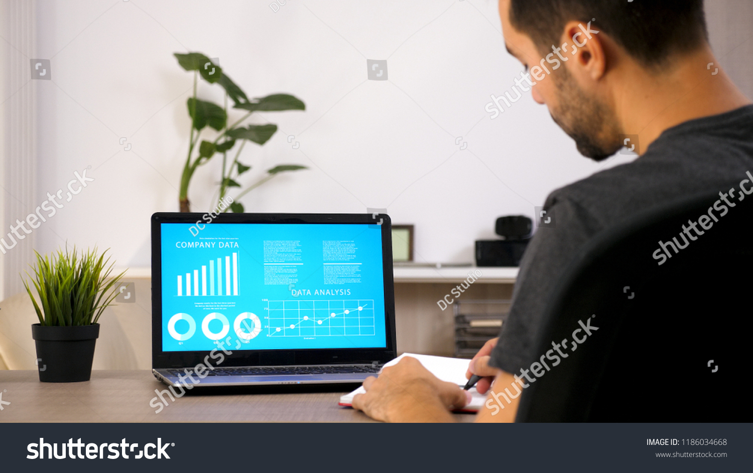 Business person working on his laptop looking at chart data in his living room #1186034668