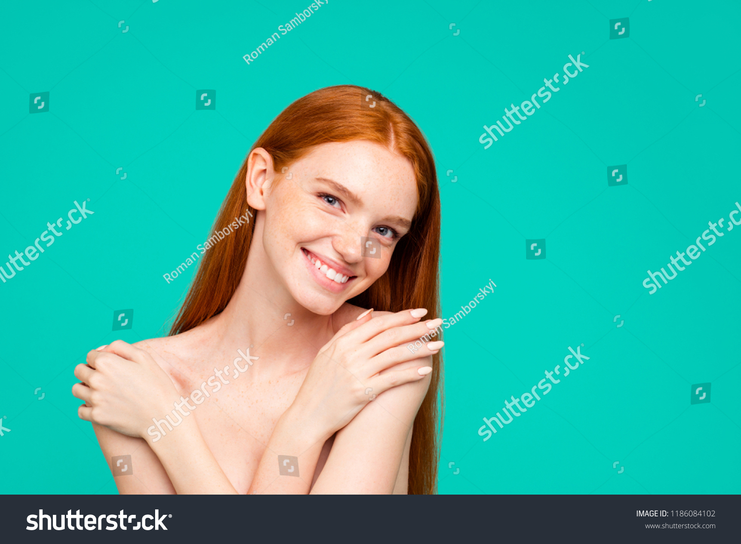Advertising concept. Portrait of nice perfect nude cheerful red-haired girl with shiny pure clean fresh smooth flawless skin, embracing herself, isolated over green turquoise background #1186084102