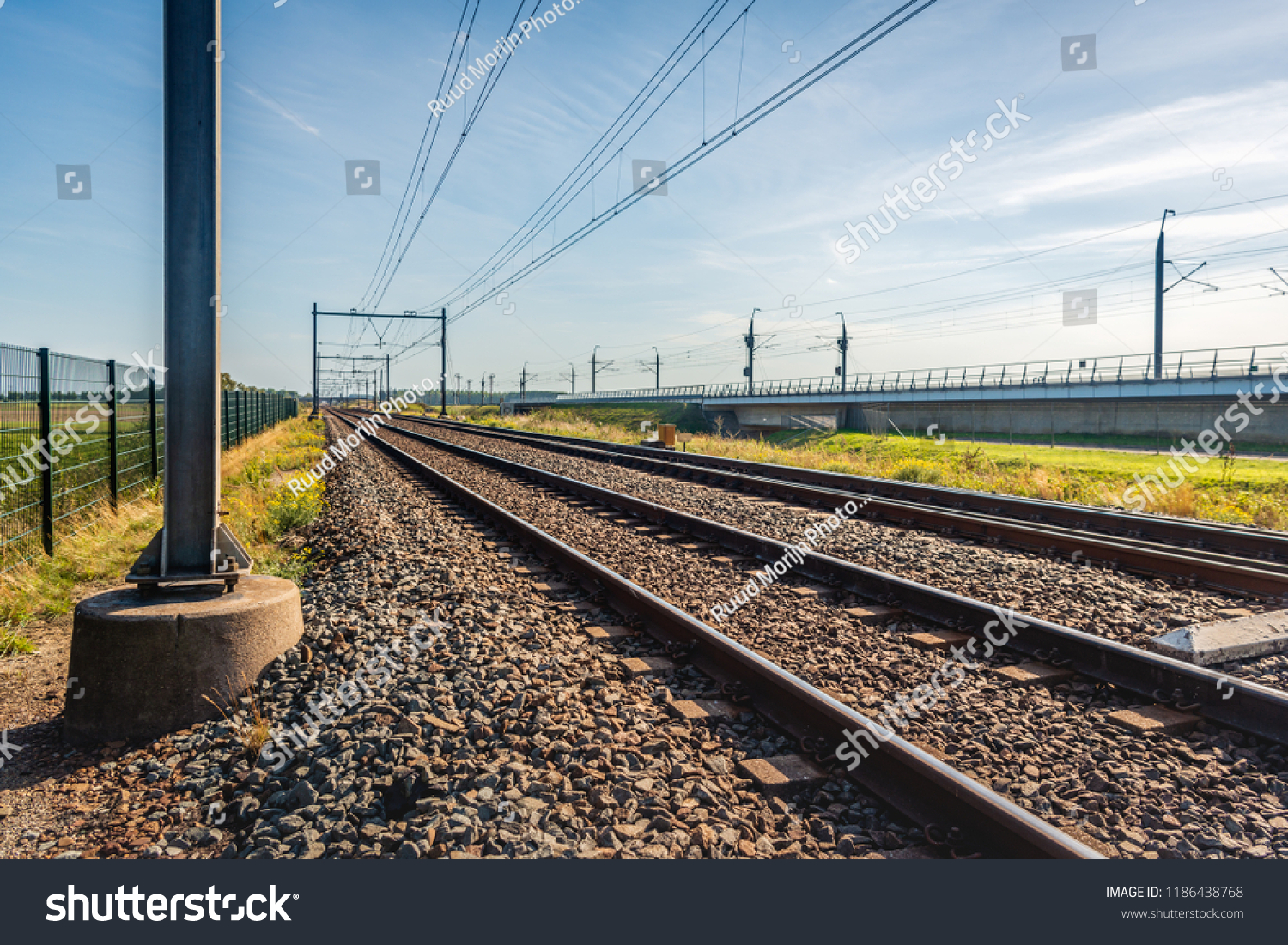 Seeminly endless train tracks on concrete sleepers and basalt gravel in the Netherlands. The photo was taken on a sunny summer day near the village of Lage Zwaluwe. In the background is the HSL line. #1186438768