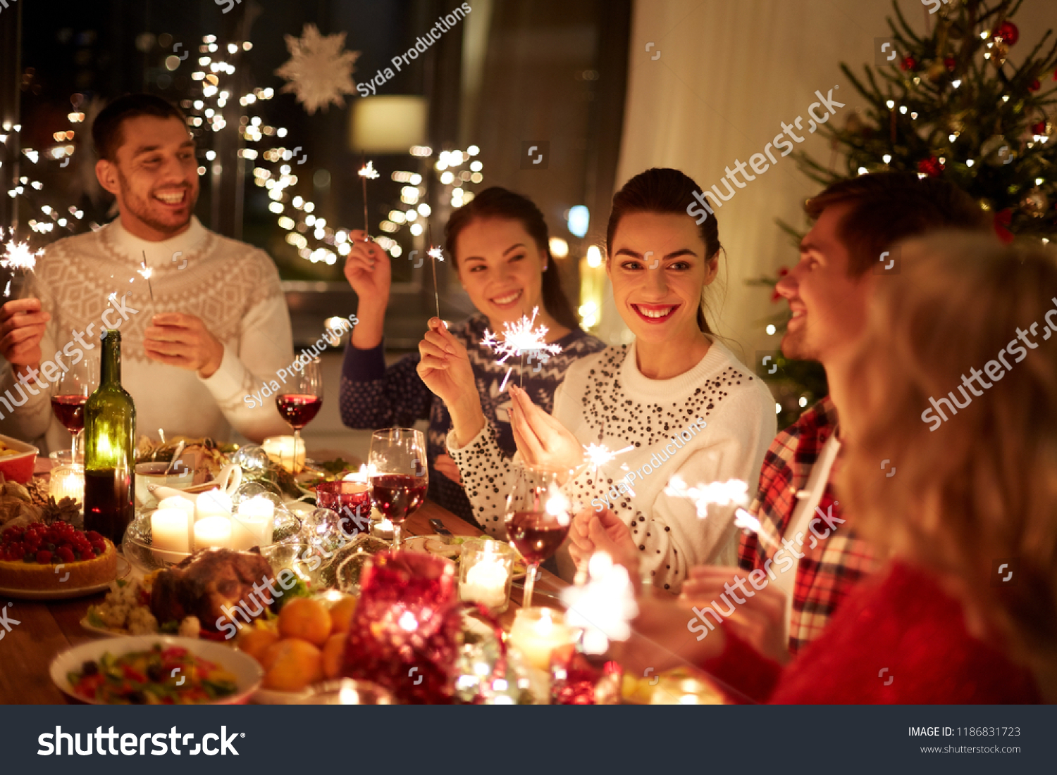 winter holidays and people concept - happy friends with sparklers celebrating christmas at home feast #1186831723