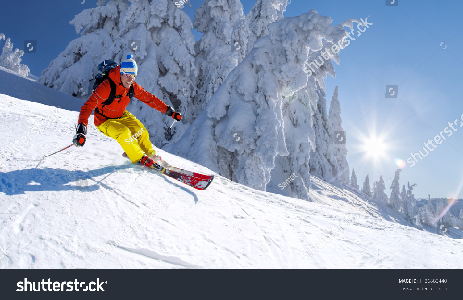 Skier skiing downhill in high mountains against blue sky #1186883440